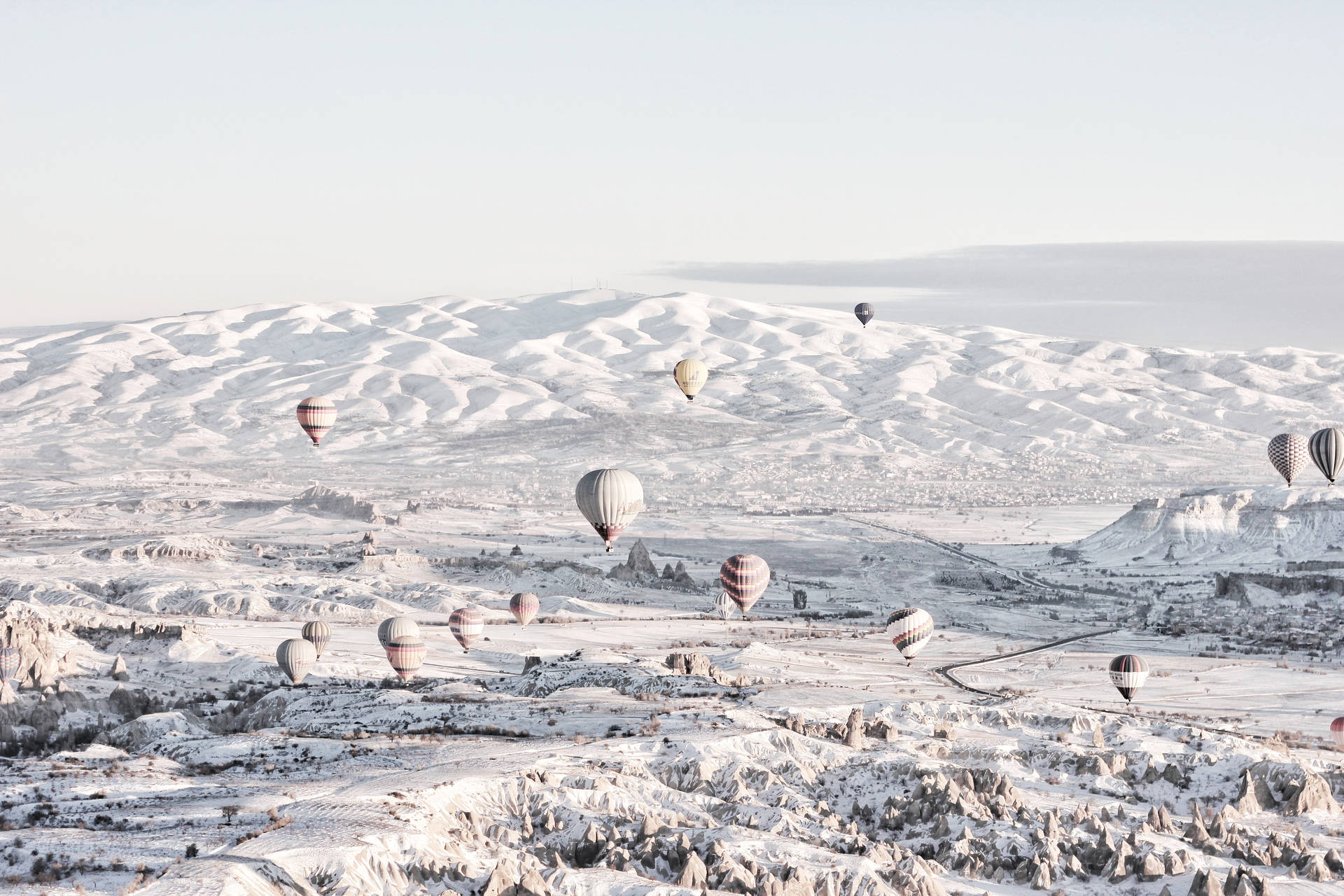 熱氣球漂浮在白雪覆蓋的山地地形上。
