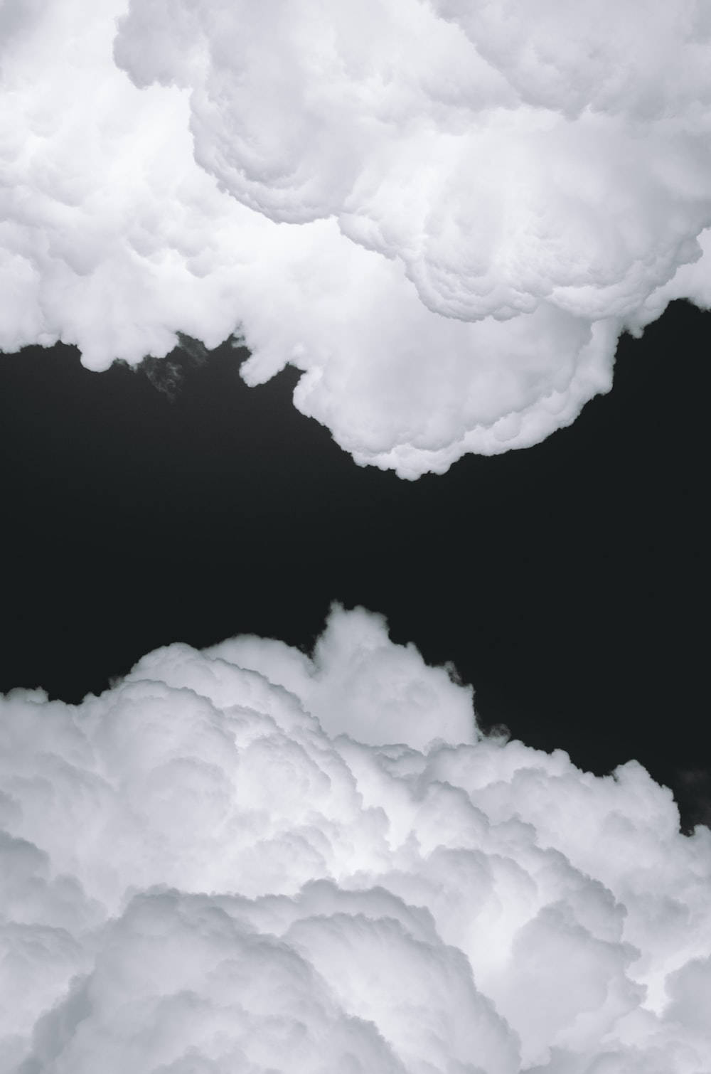 純白平面上的寧靜感 壁紙 — 豐盈的白雲框住深邃的黑色虛空，營造出戲劇性的天體對比。