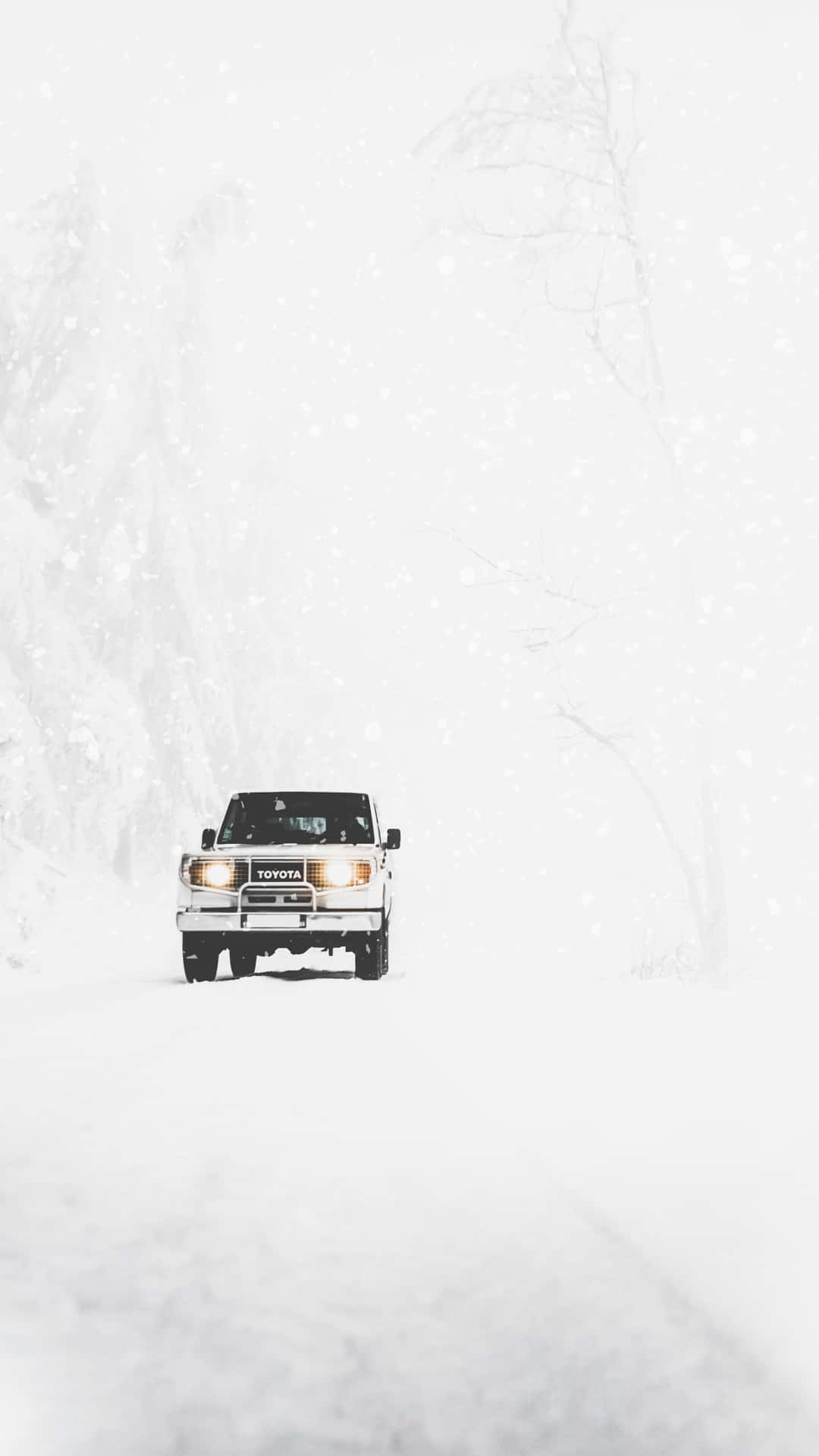 白色貨車在冬季森林的猛烈暴風雪中行駛。