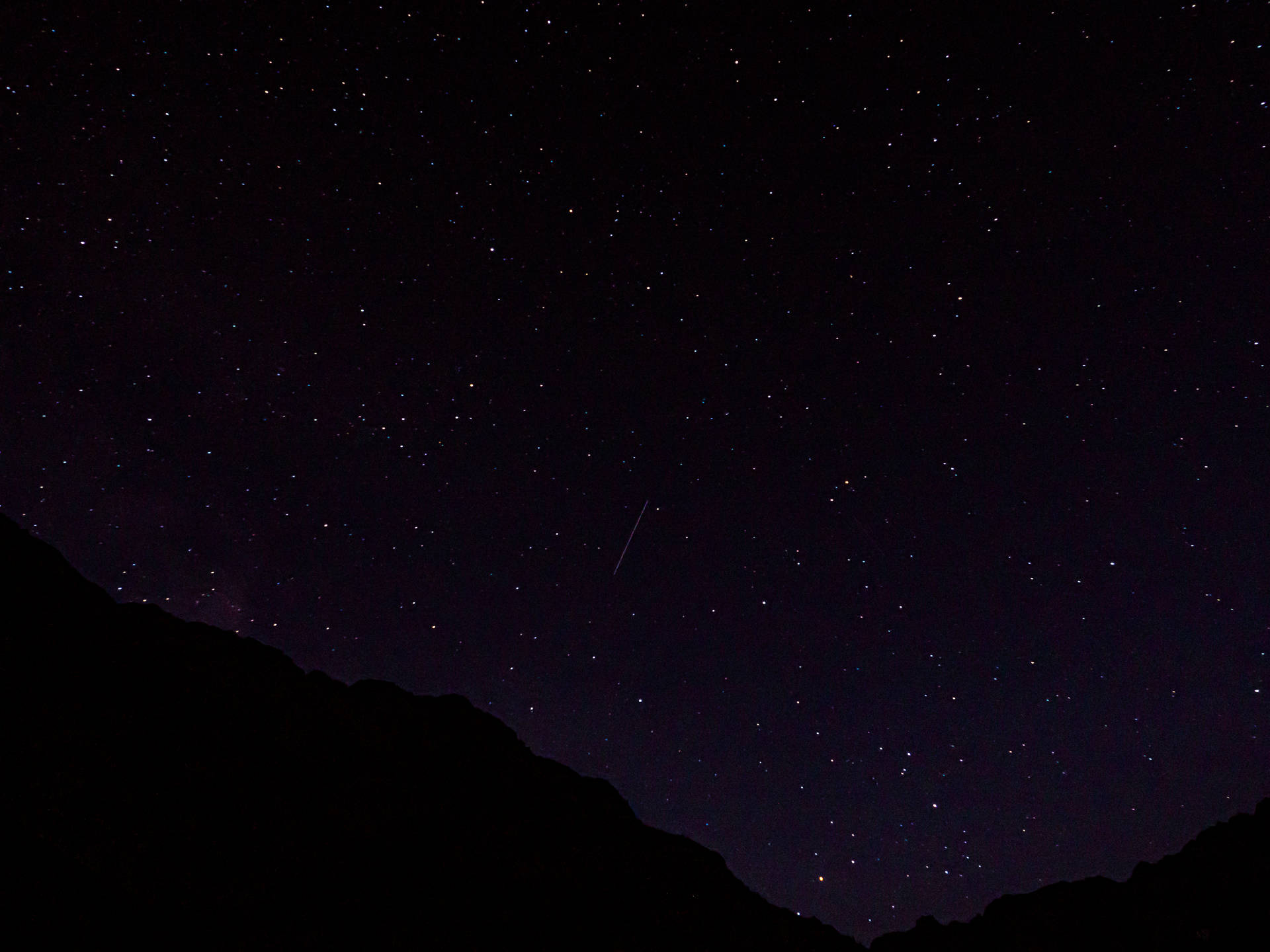 流星越過山脈剪影，在星空夜空下