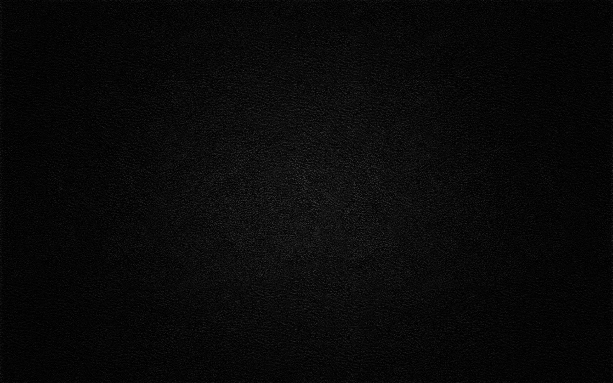 純黑底配皮革紋理 壁紙 — 黑色光滑皮革表面的特寫，帶有細微的粒面紋理和柔和的光線漸變。