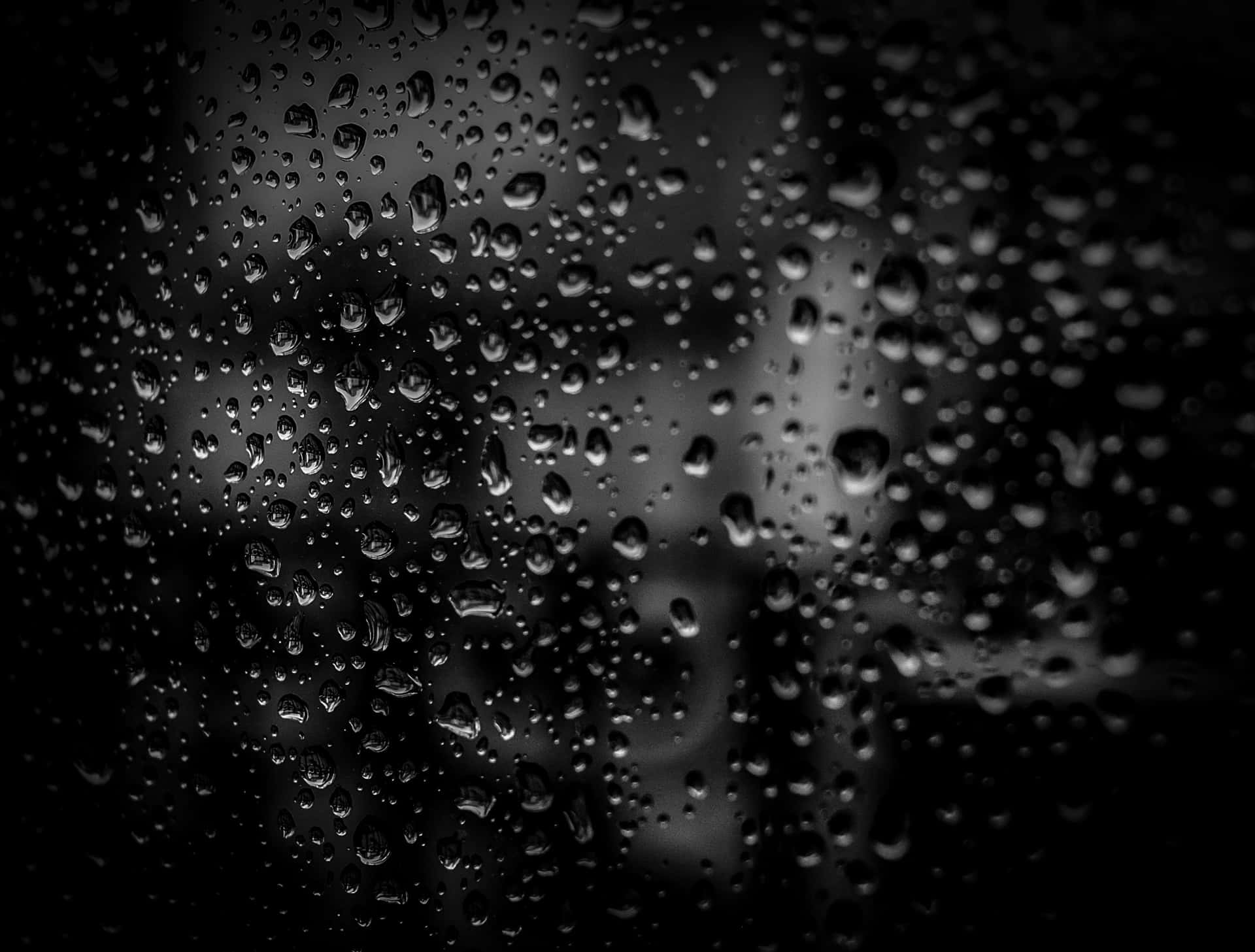 單色模糊背景下的玻璃上的雨滴。