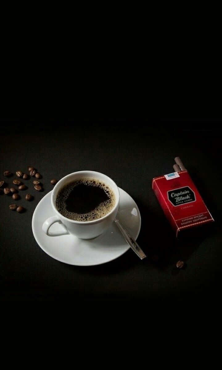 Black Coffee 桌布 壁紙 — 純黑背景突顯白色咖啡杯、湯匙、散落的咖啡豆，以及旁邊的紅色香煙包。