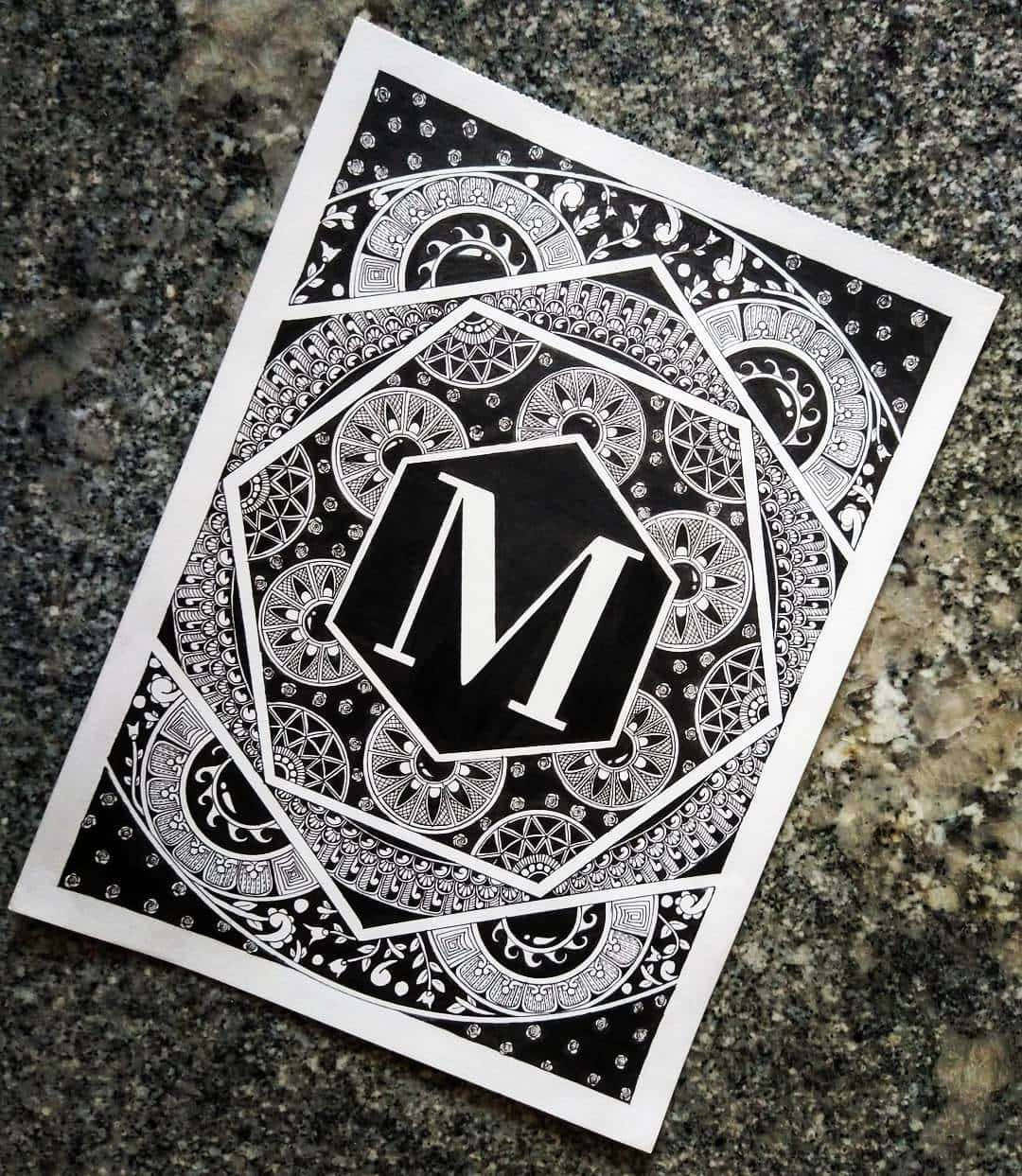 m 桌布 壁紙 — 紙上一個六邊形內的黑白字母組合'M'，周圍環繞著複雜的曼陀羅圖案。