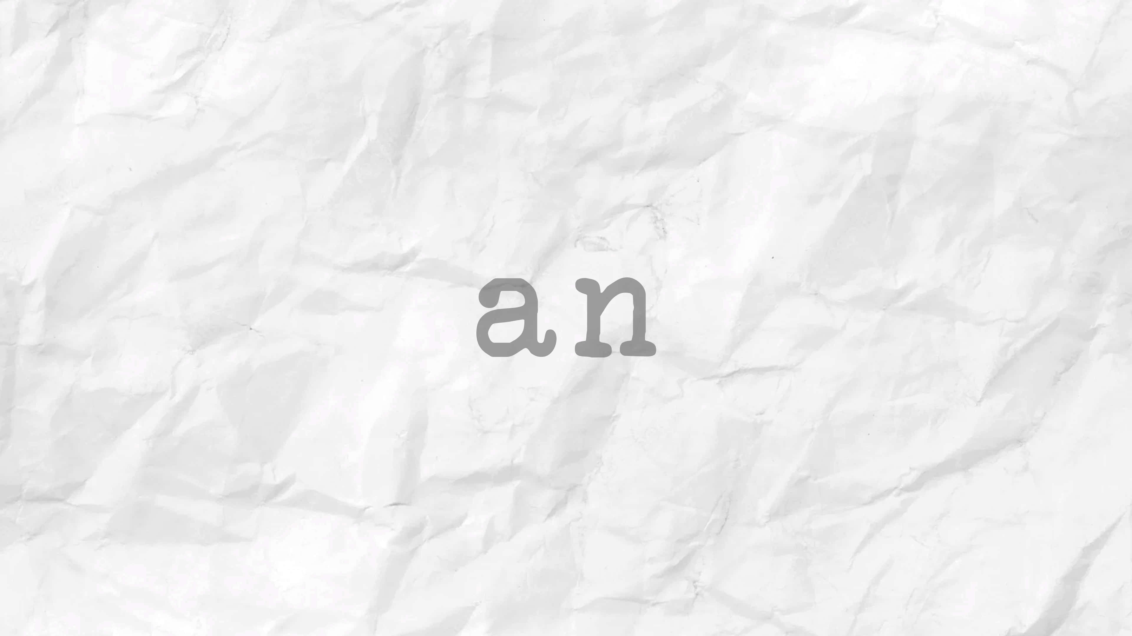 紙上潦草的「an」字 壁紙 — 灰色字體嘅「an」字詞放置喺有紋理嘅白色皺紙背景上。