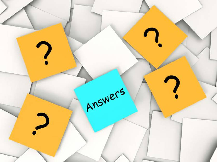 紙張上的問題與答案 壁紙 — 一張藍色便利貼，上面寫著 'Answers'，周圍散落著帶有問號的黃色便利貼，背景為白色紙張。