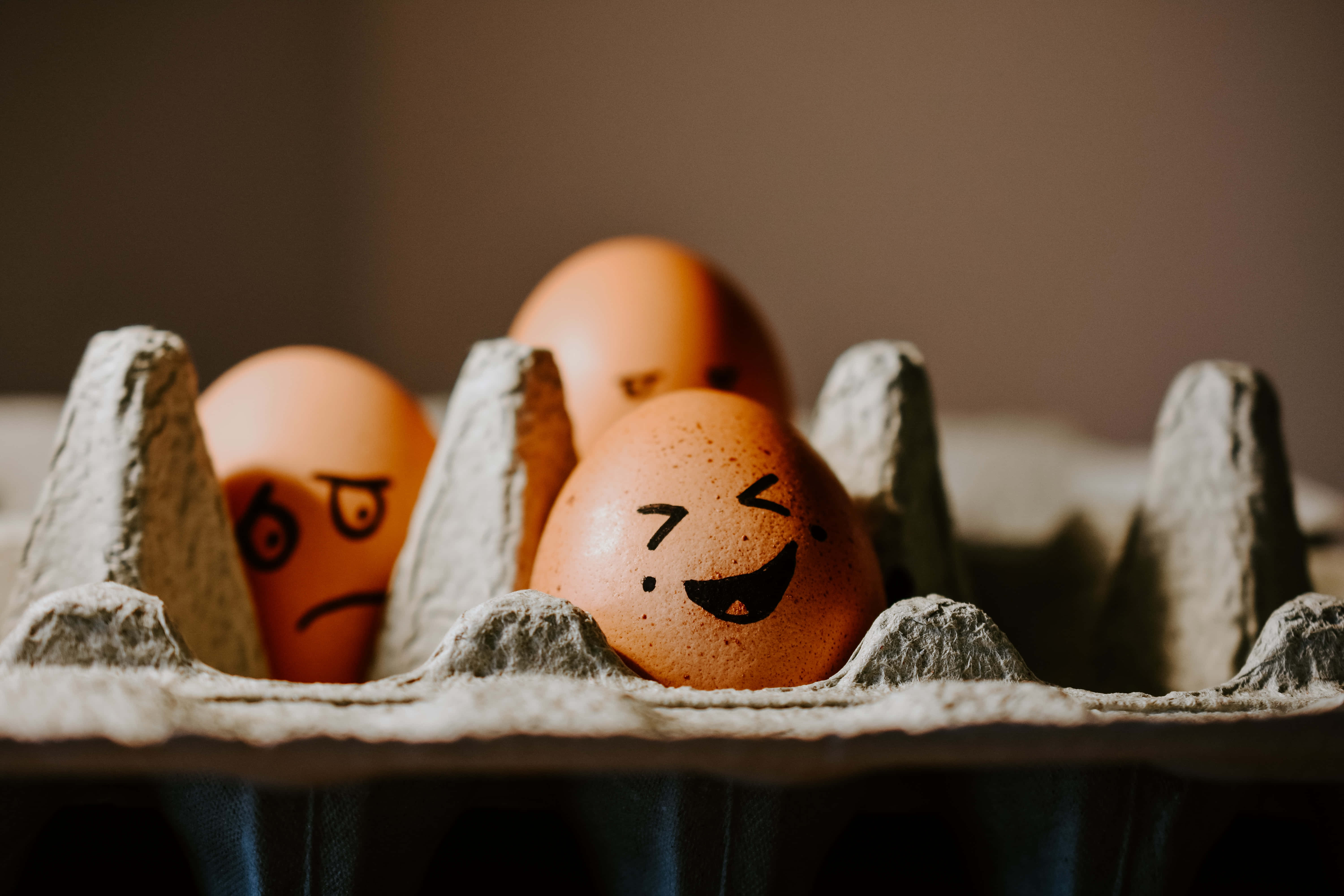 Brown Eggs 桌布 壁紙 — 紙板盒內啡色雞蛋的特寫，上面畫有一個微笑和一個皺眉的表情。
