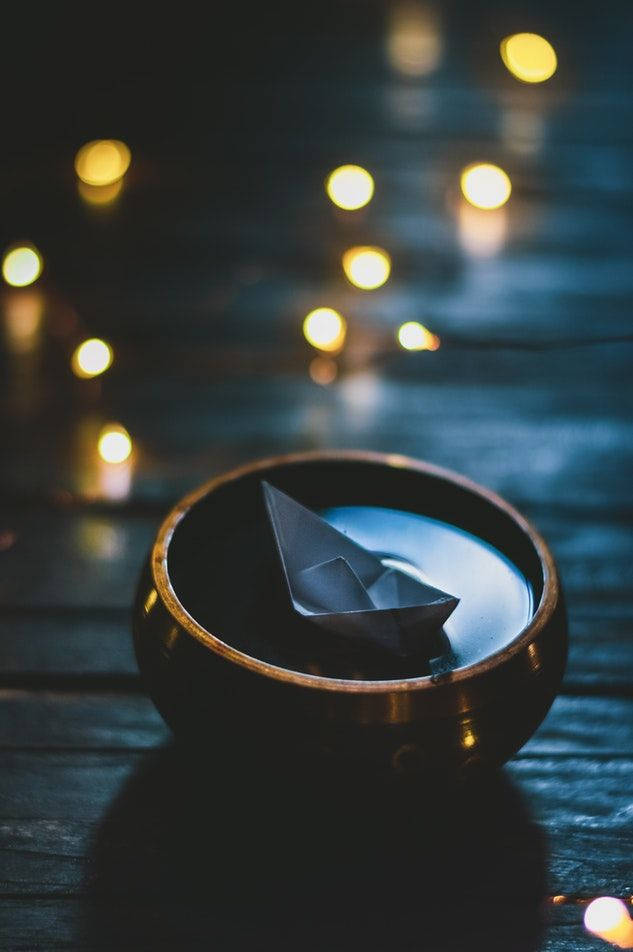 木碗中的紙船，背景中串燈柔和發光。