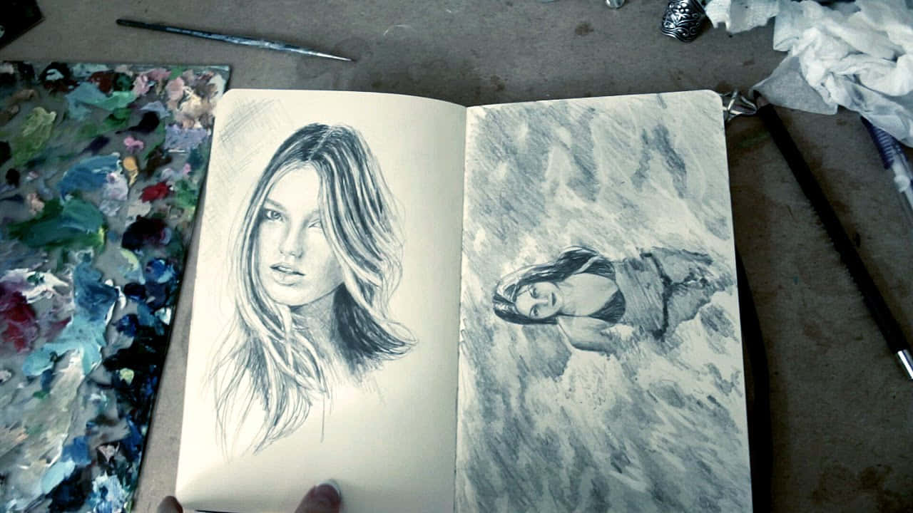 素描簿中的兩幅女性鉛筆素描，附近有顏料調色板和畫筆。