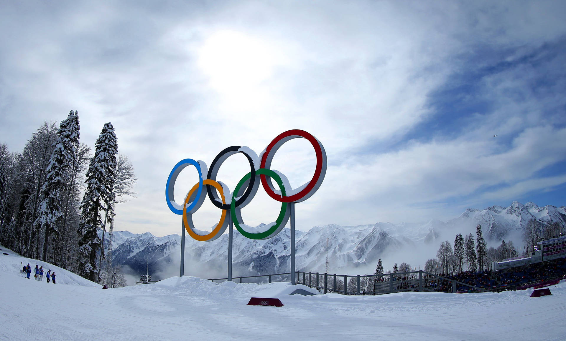 雪山環境中的奧運五環，有滑雪者和觀眾。
