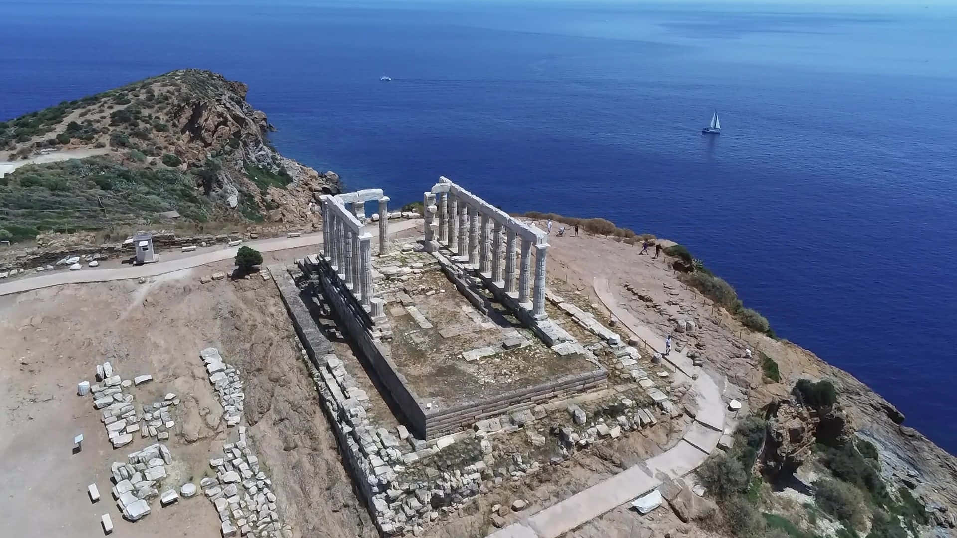 索尼翁海神廟 壁紙 — 俯瞰懸崖上古老寺廟遺址的航拍圖，遠眺深藍色大海，遠處有帆船。