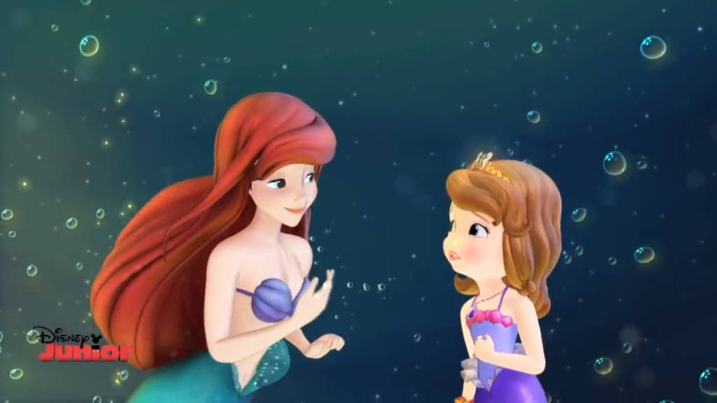 索菲亞公主與小美人魚 壁紙 — 紅髮美人魚艾莉爾喺充滿發光氣泡嘅水底場景中，向蘇菲亞公主溫暖微笑。