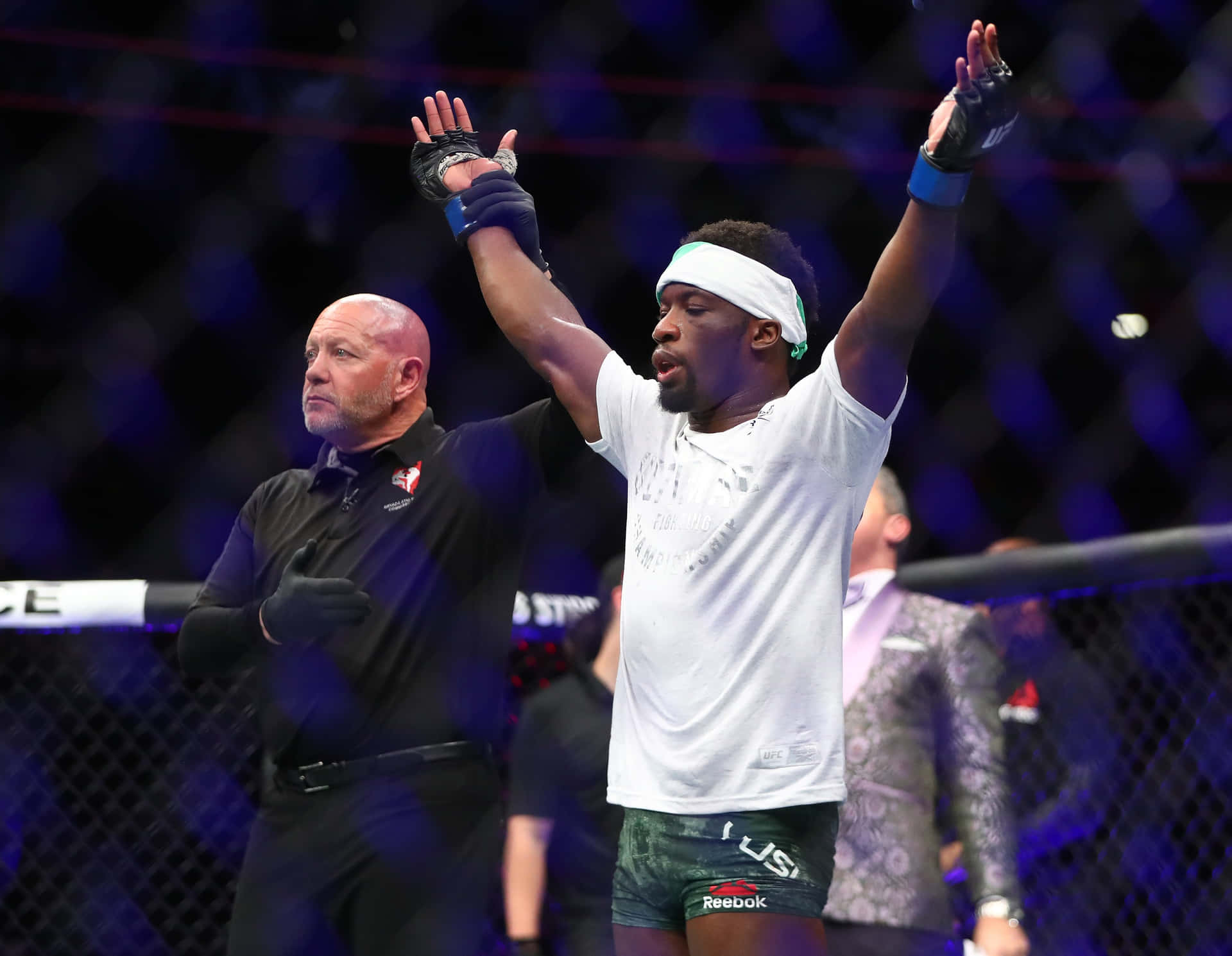 MMA選手在八角籠中高舉雙臂慶祝勝利。