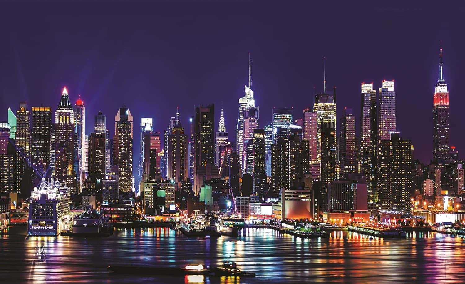 紐約市天際線的夜景，有燈火通明的摩天大樓和水面倒影。