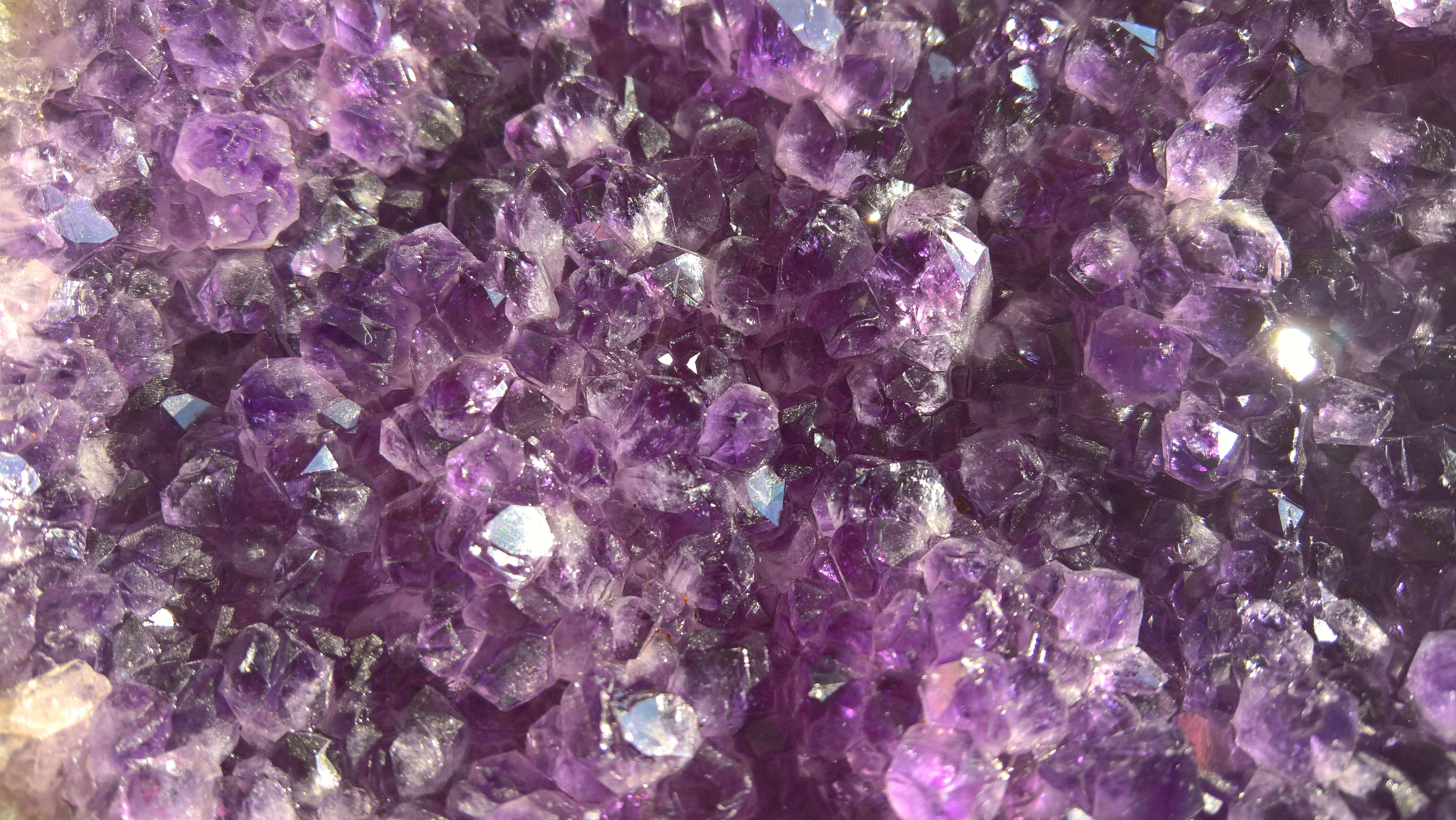 紫水晶晶體形成 壁紙 — 一組密集的閃亮紫色紫水晶晶體特寫，其鋒利的刻面捕捉光線。