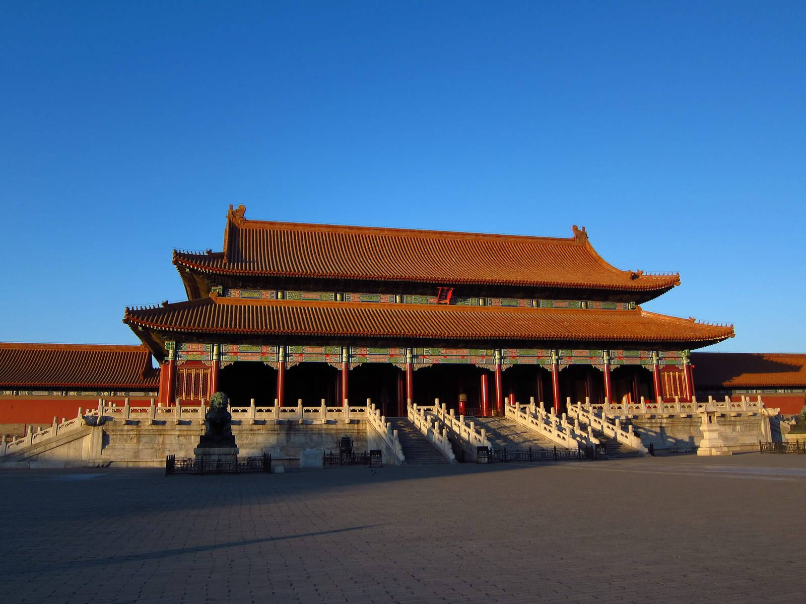 令人印象深刻的中國古代宮殿，橙色屋頂和紅色柱子沐浴在金色的夕陽中。