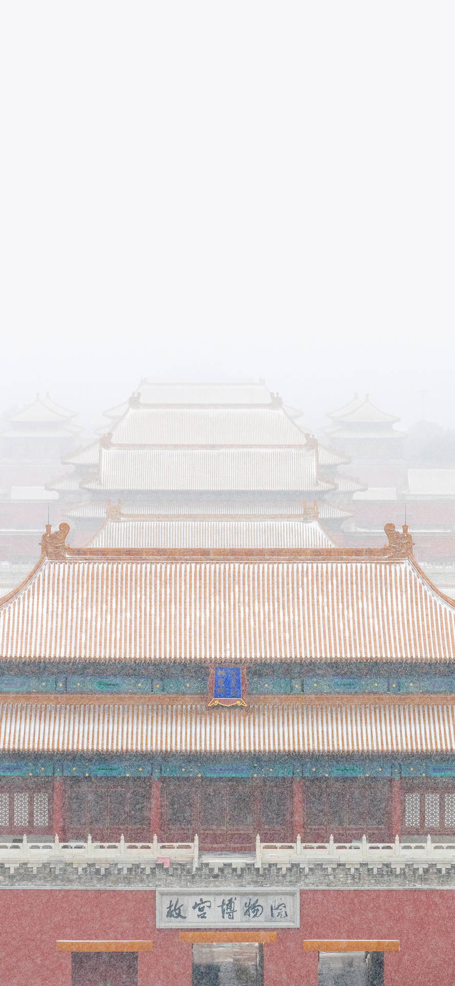 在朦朧的冬日天空下，故宮屋頂被白雪覆蓋。
