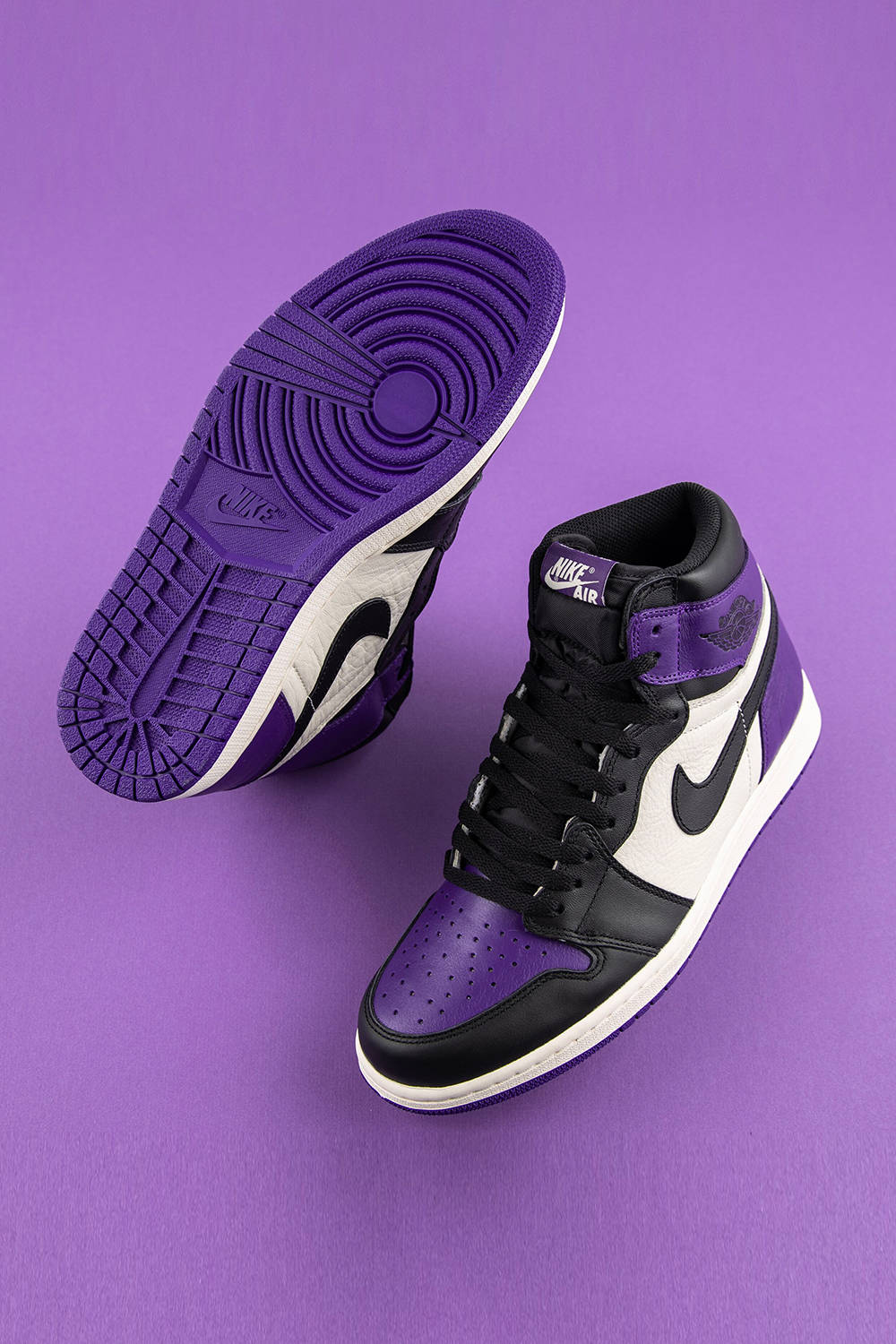紫、黑、白色Nike Air Jordan 1運動鞋，紫色背景。
