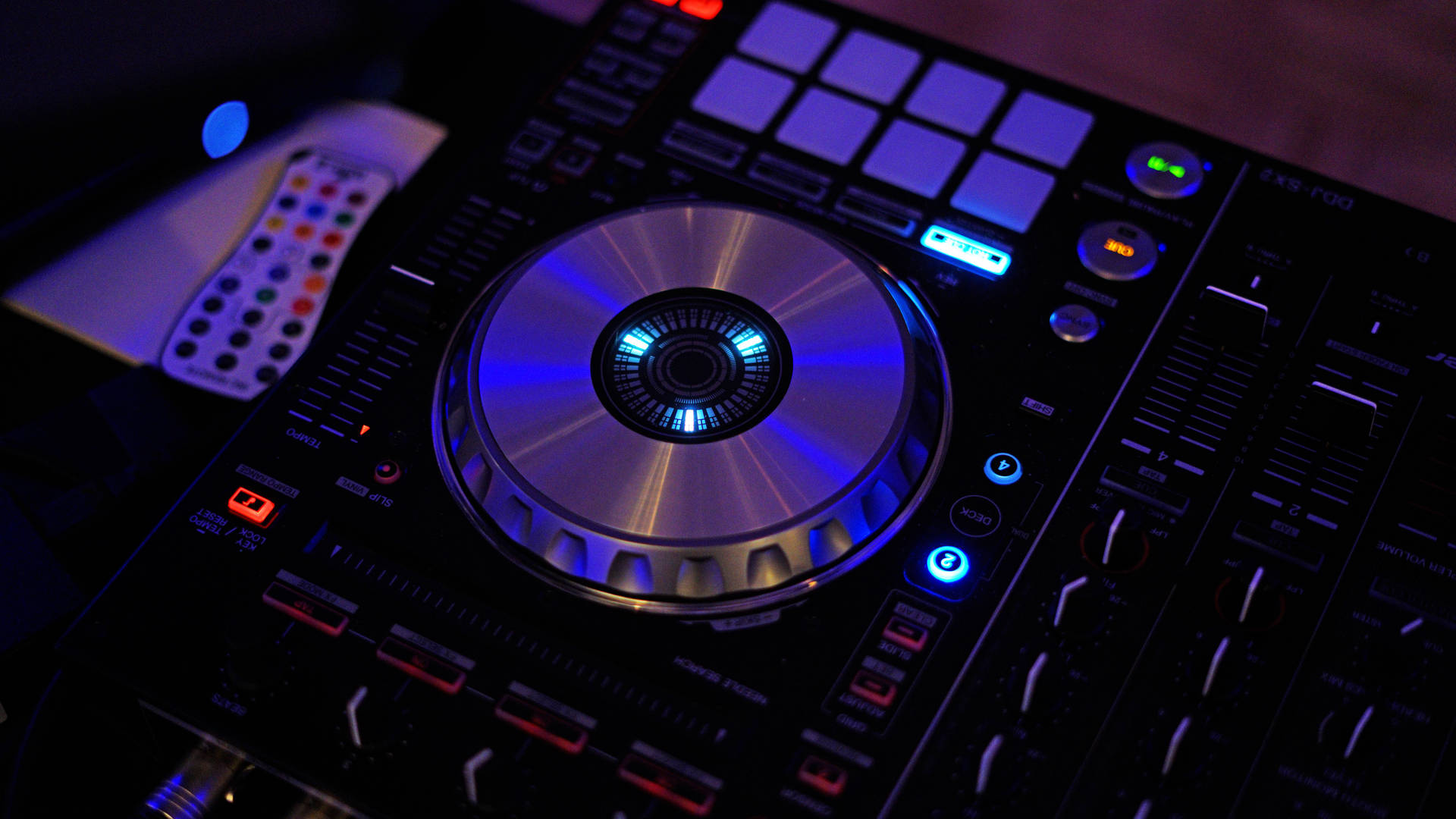 在黑暗的俱樂部中發出藍色和紅色光的 DJ 控制器。