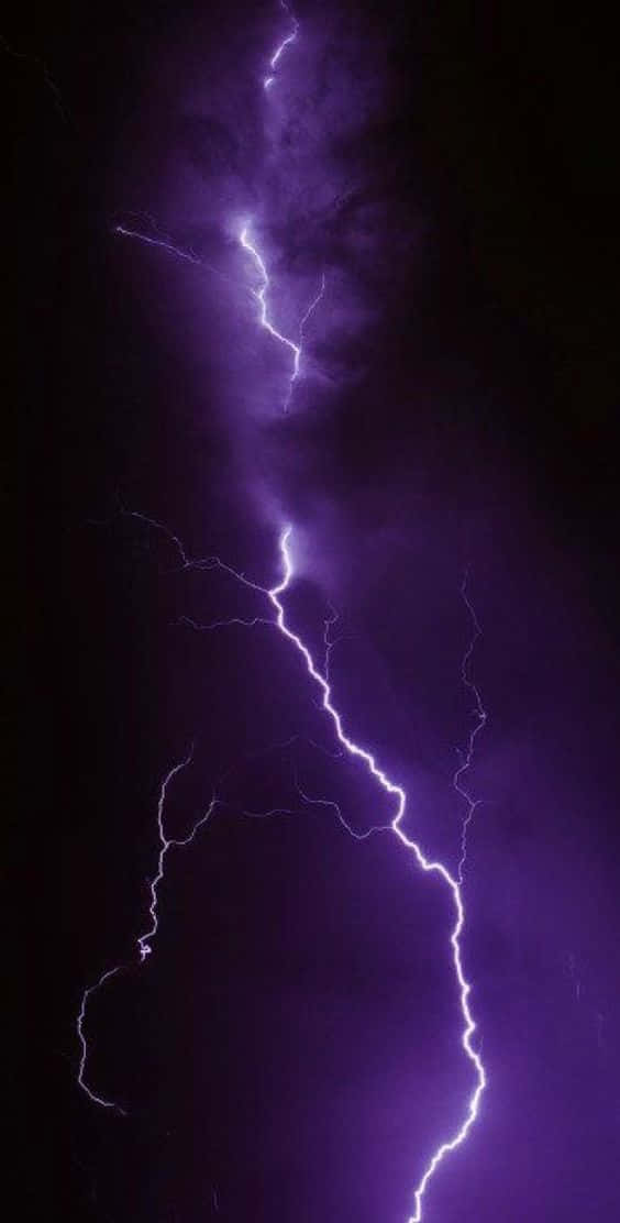 一道強大的紫色閃電照亮了黑暗的暴風雨天空。