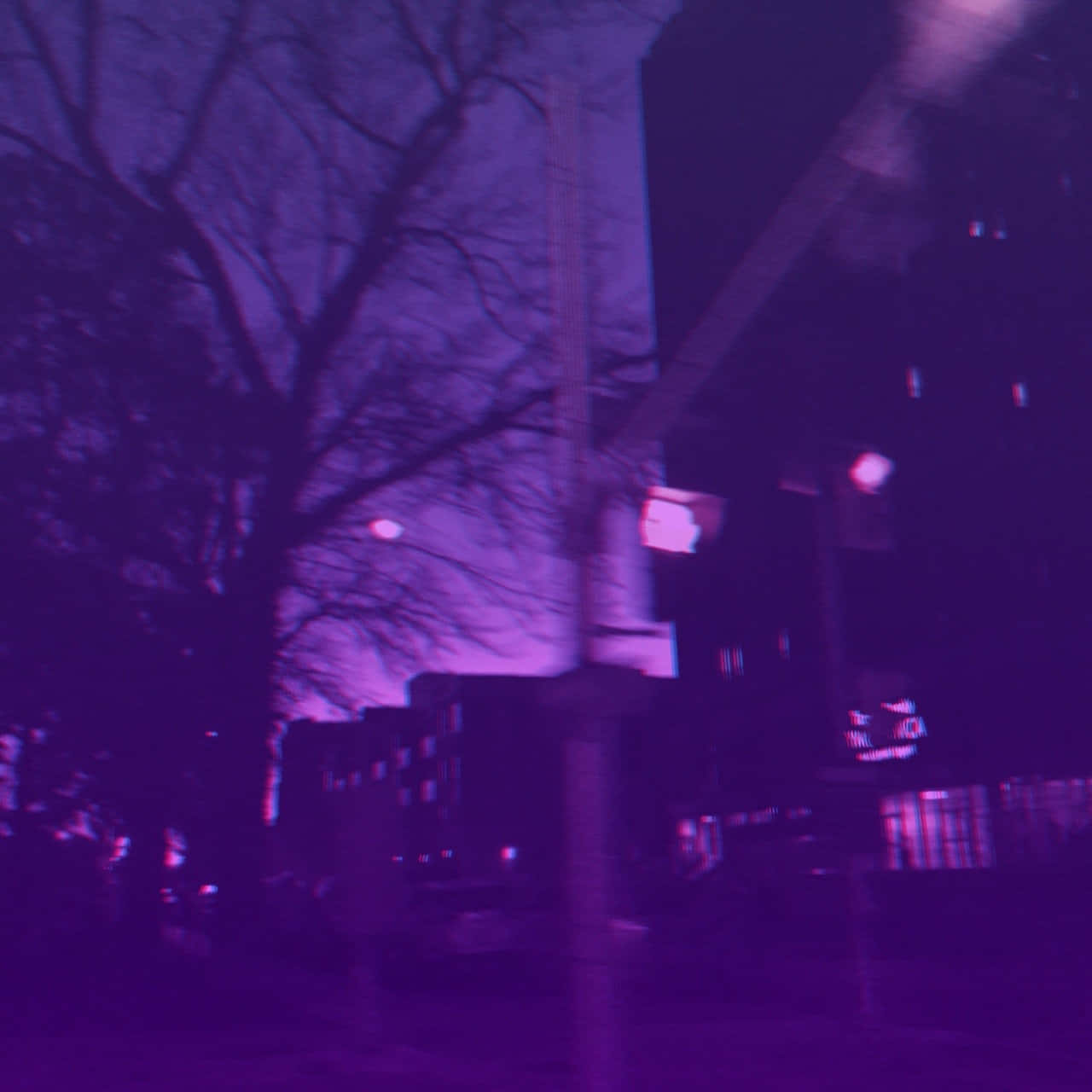紫色天空 壁紙 — 一條夜間動態模糊的城市街道，沐浴在強烈的紫色光線中，光禿的樹枝在發光的建築物襯托下形成剪影。