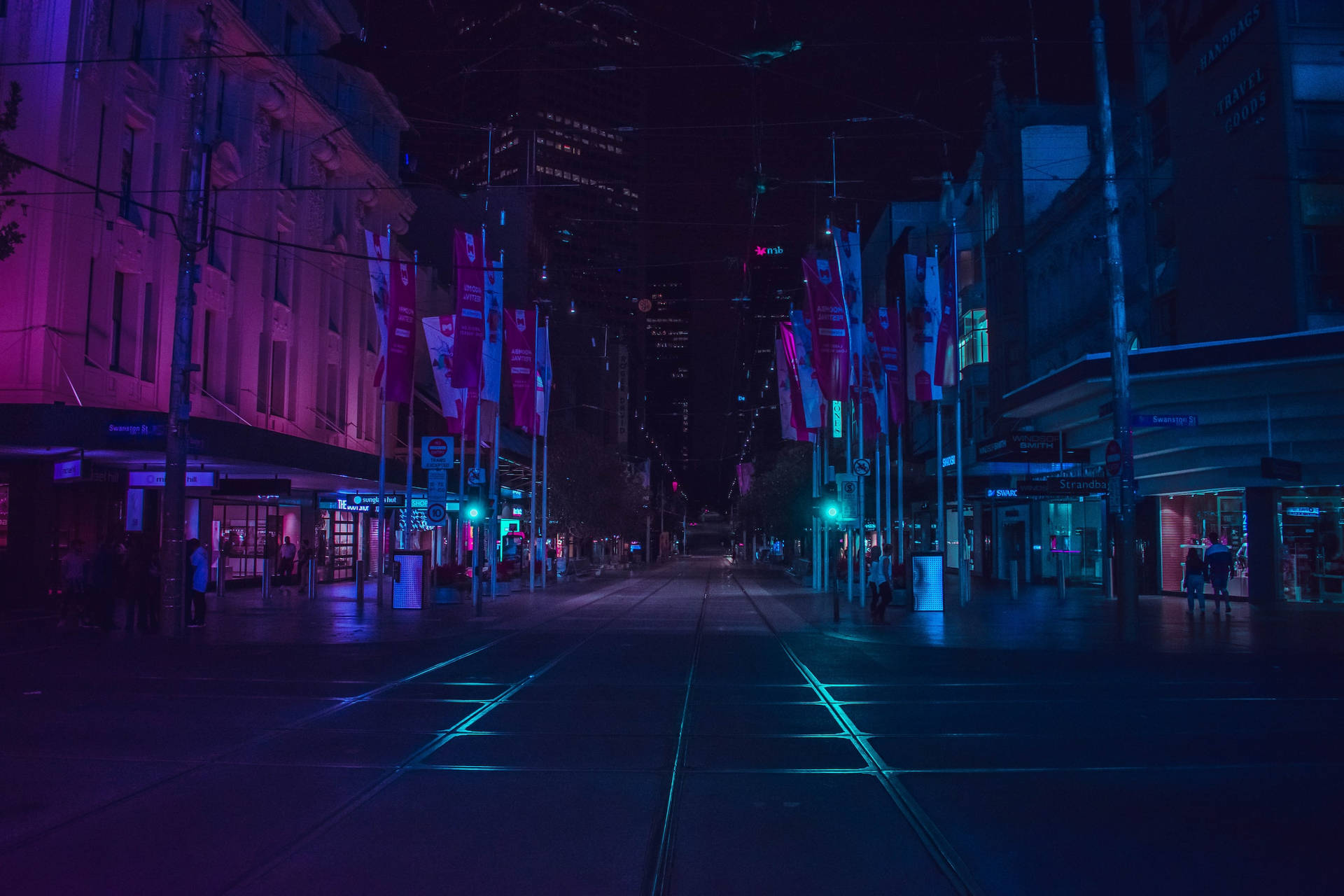 夜晚霓虹燈照亮城市街道，有電車軌道和發光招牌。