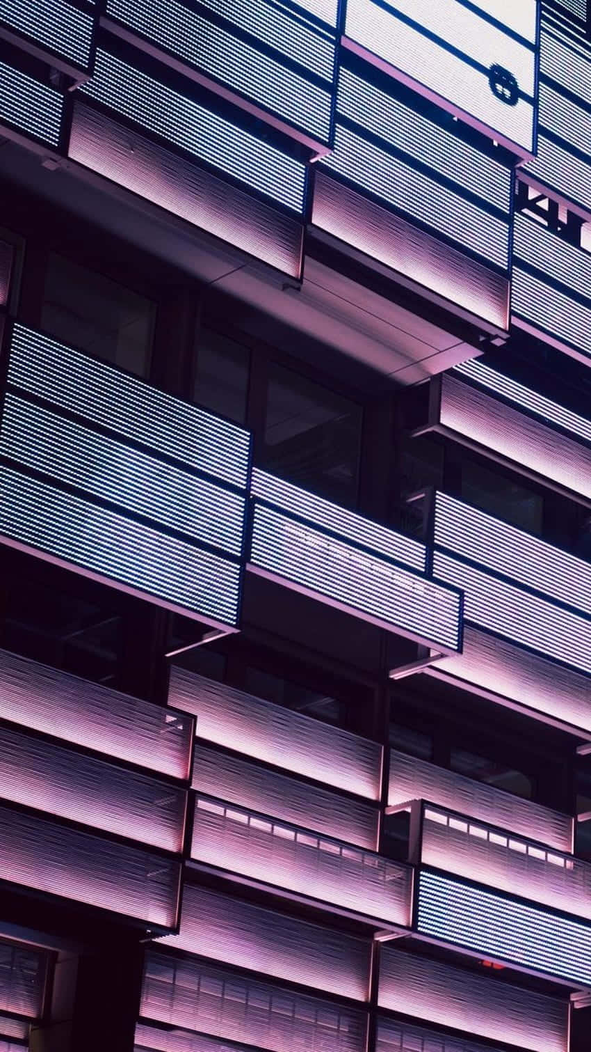 夜晚現代建築物外牆，帶有發光的紫色和白色水平燈光。