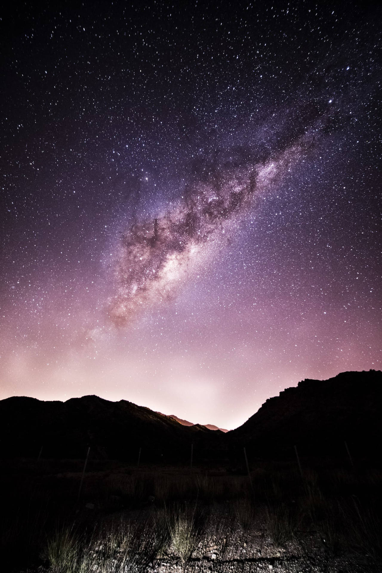 銀河系在夜晚的山巒剪影上發光