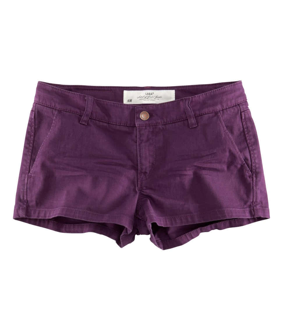 Purple Shorts 桌布 壁紙 — 紫色牛仔短褲，帶有鈕扣和品牌標籤，平放在白色背景上。