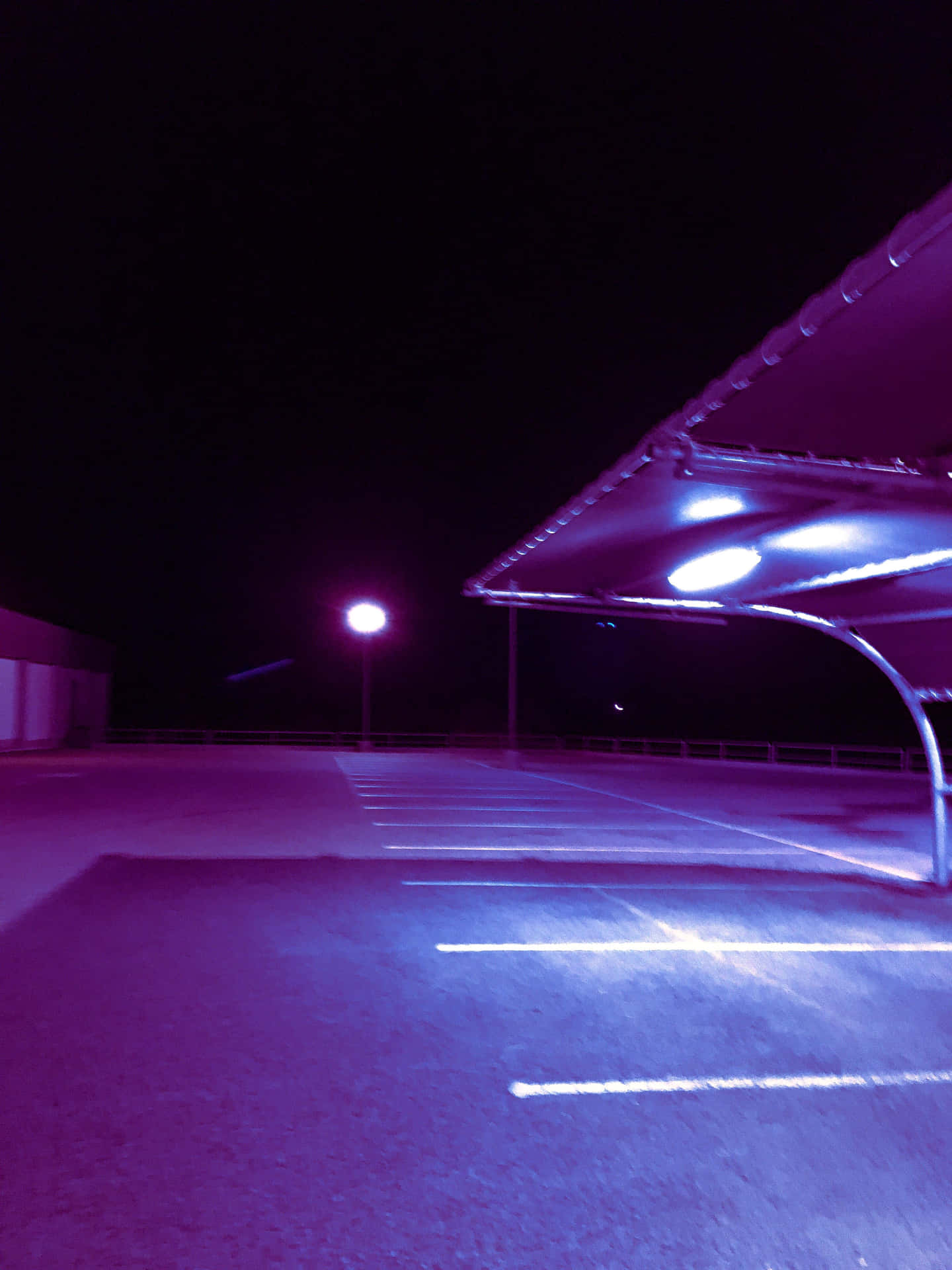 夜晚空無一人的停車場，在紫色和藍色人造燈光下。