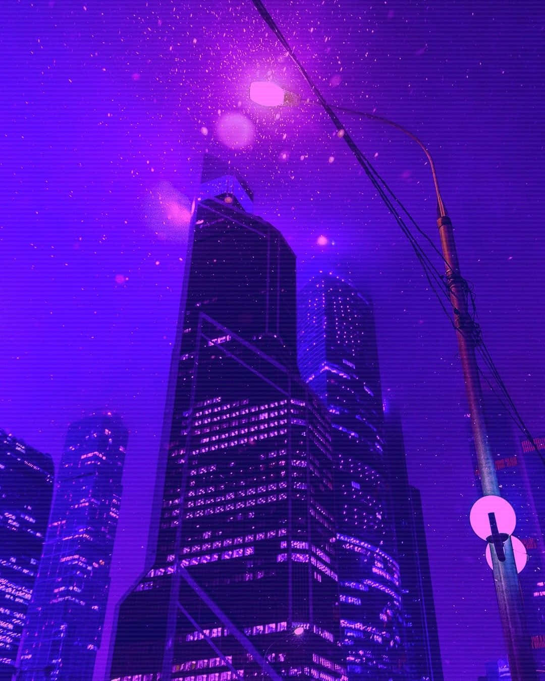 紫色美學城市燈光建築圖 壁紙 — 高聳的摩天大樓在充滿活力的紫色夜空下發光，伴隨著漂浮的粒子和霓虹街燈。