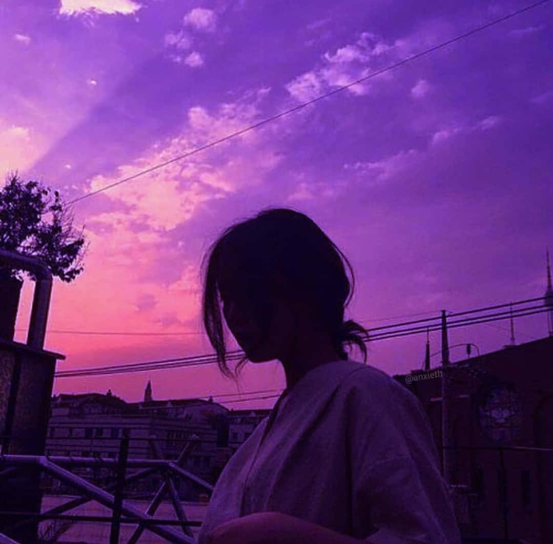 紫色美學女性剪影天空圖 壁紙 — 一個人嘅剪影，喺有電線嘅城市景觀上凝視住充滿活力嘅紫色同粉紅色日落。