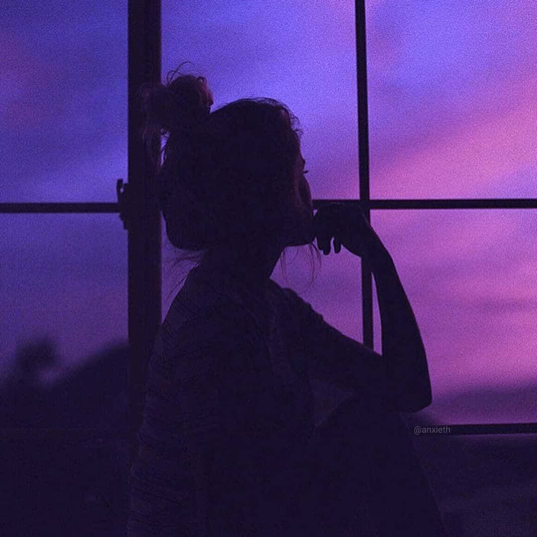 紫色美學窗邊女性影子天空圖 壁紙 — 一個束著髮髻的人的剪影，正透過窗戶凝視著充滿活力的紫色和粉紅色暮色天空。