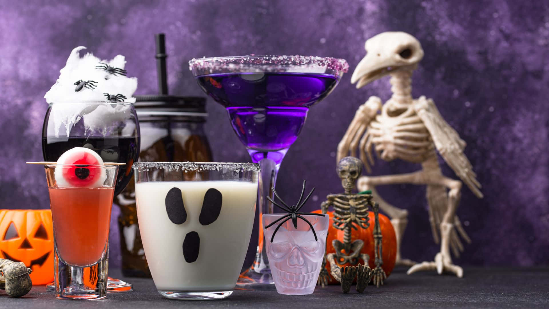 Spooky Cocktails 桌布 壁紙 — 紫色背景上，帶有眼球、蜘蛛和骷髏等恐怖裝飾的萬聖節雞尾酒。