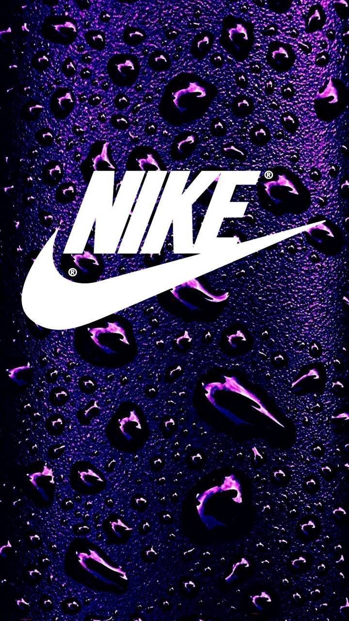 紫色背景的耐克標誌 壁紙 — 白色Nike標誌在深紫色表面上閃耀，表面點綴著閃閃發光的水滴。