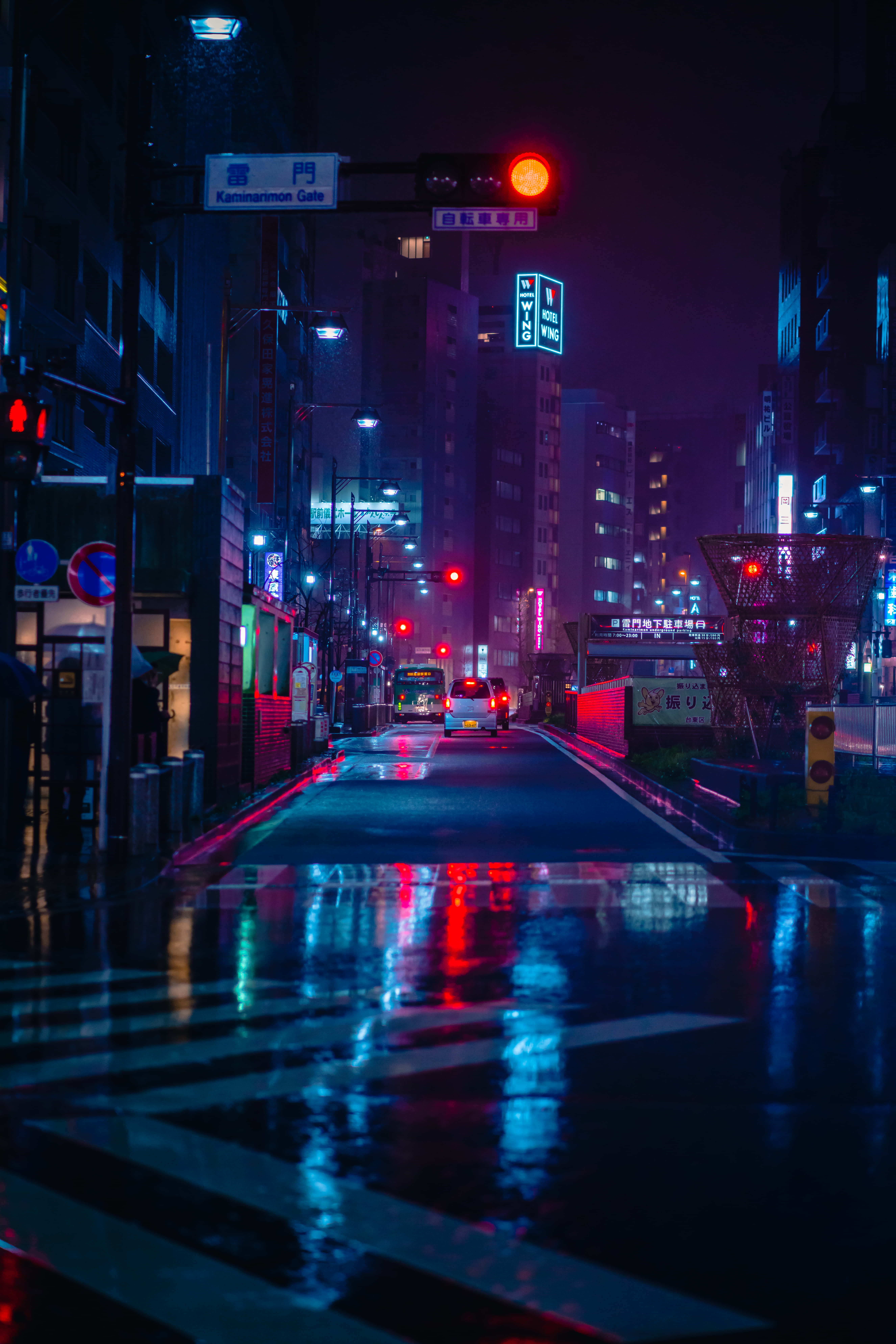 紫色霓虹美學佈置 壁紙 — 雨濕的東京霓虹燈街道在夜晚反射出交通燈和招牌的鮮豔紅藍燈光。