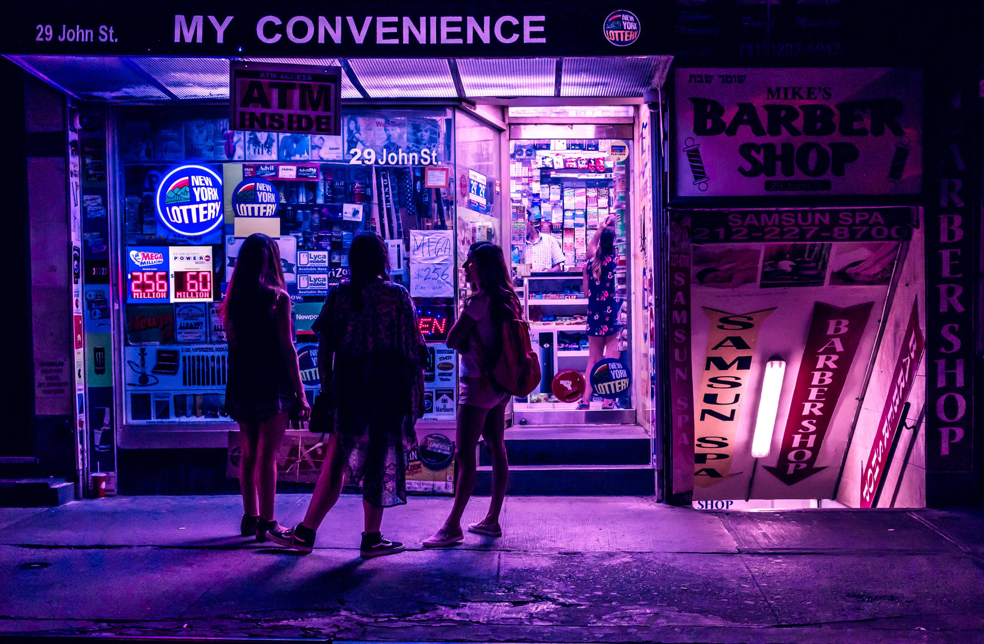 三個人站在一間發光的紫色便利店和理髮店外，在夜晚。