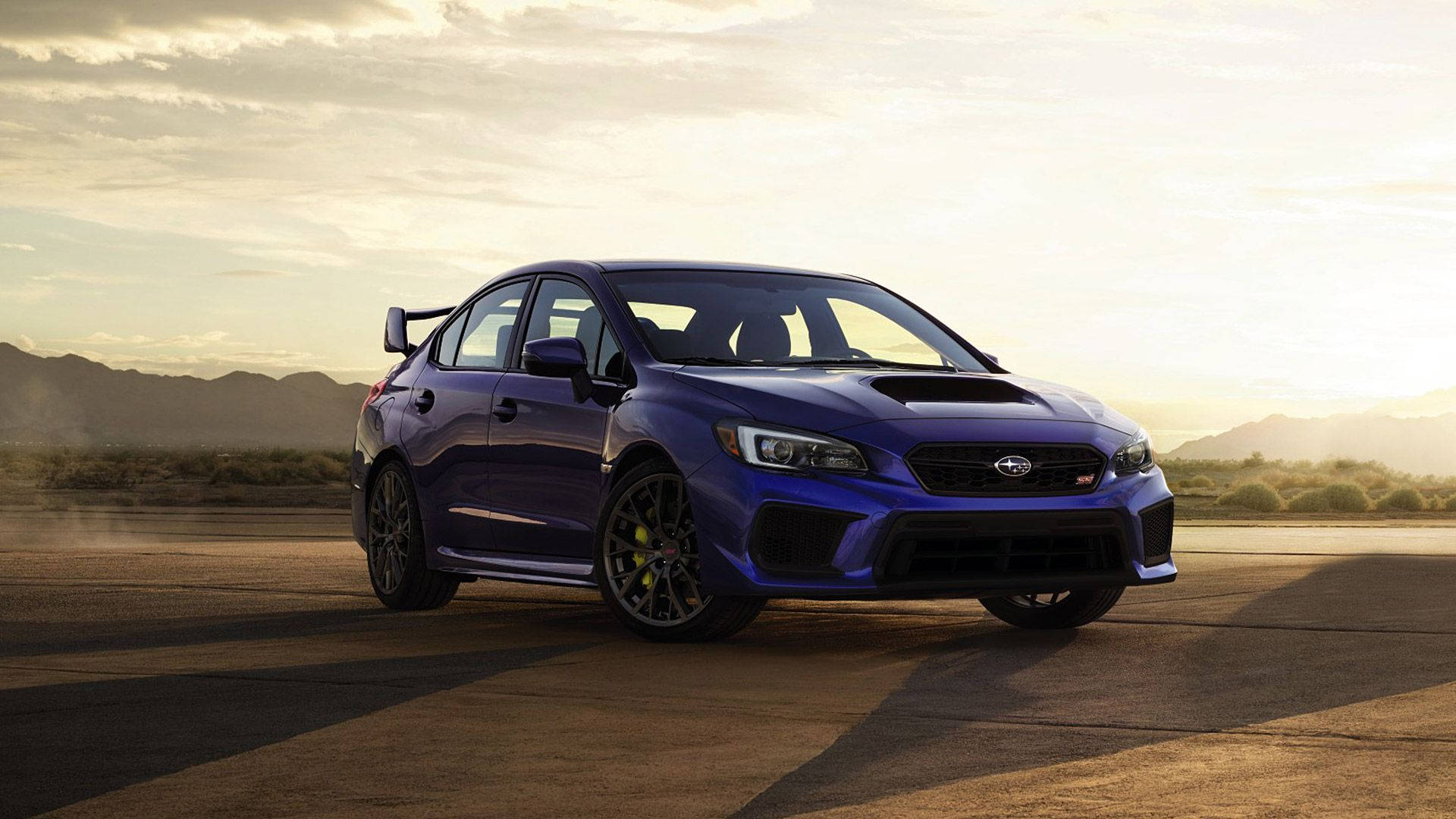 紫藍金屬斯巴魯WRX STI 壁紙 — 一輛充滿活力的藍色 Subaru WRX STI 跑車停泊在沙漠賽道上，背景是山脈，正值黃金時刻。