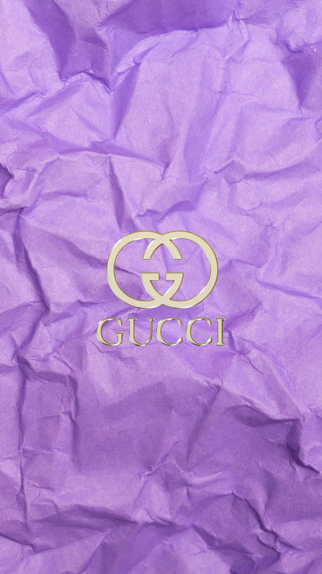 紫調 Gucci 品牌標誌與皺紙背景 壁紙 — 金色Gucci標誌放置在帶有紋理的皺褶紫色紙上，光線柔和。