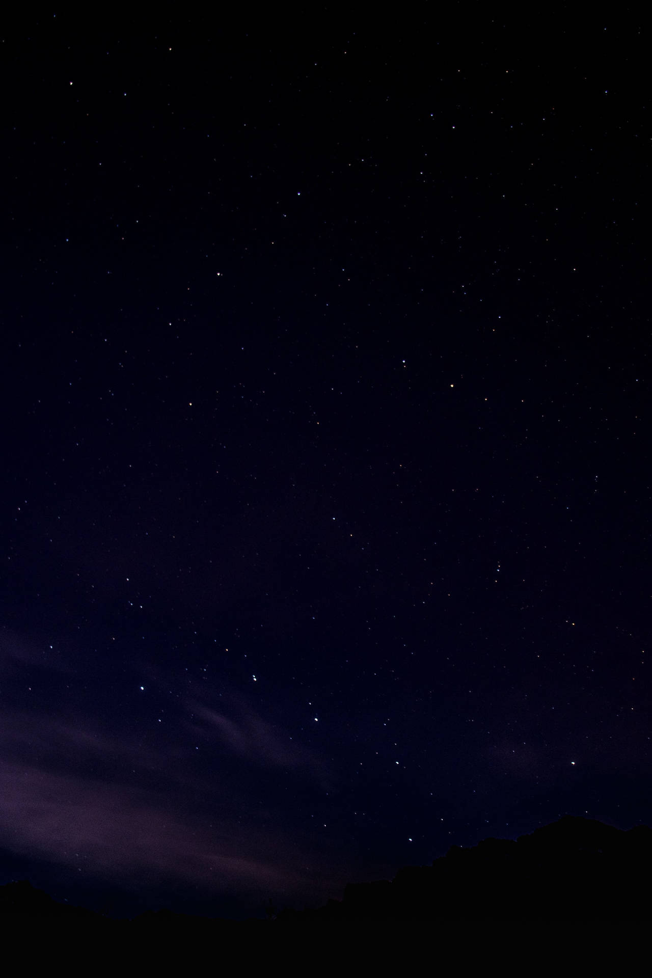 繁星點點的夜空，帶有紫色雲朵和山巒輪廓。