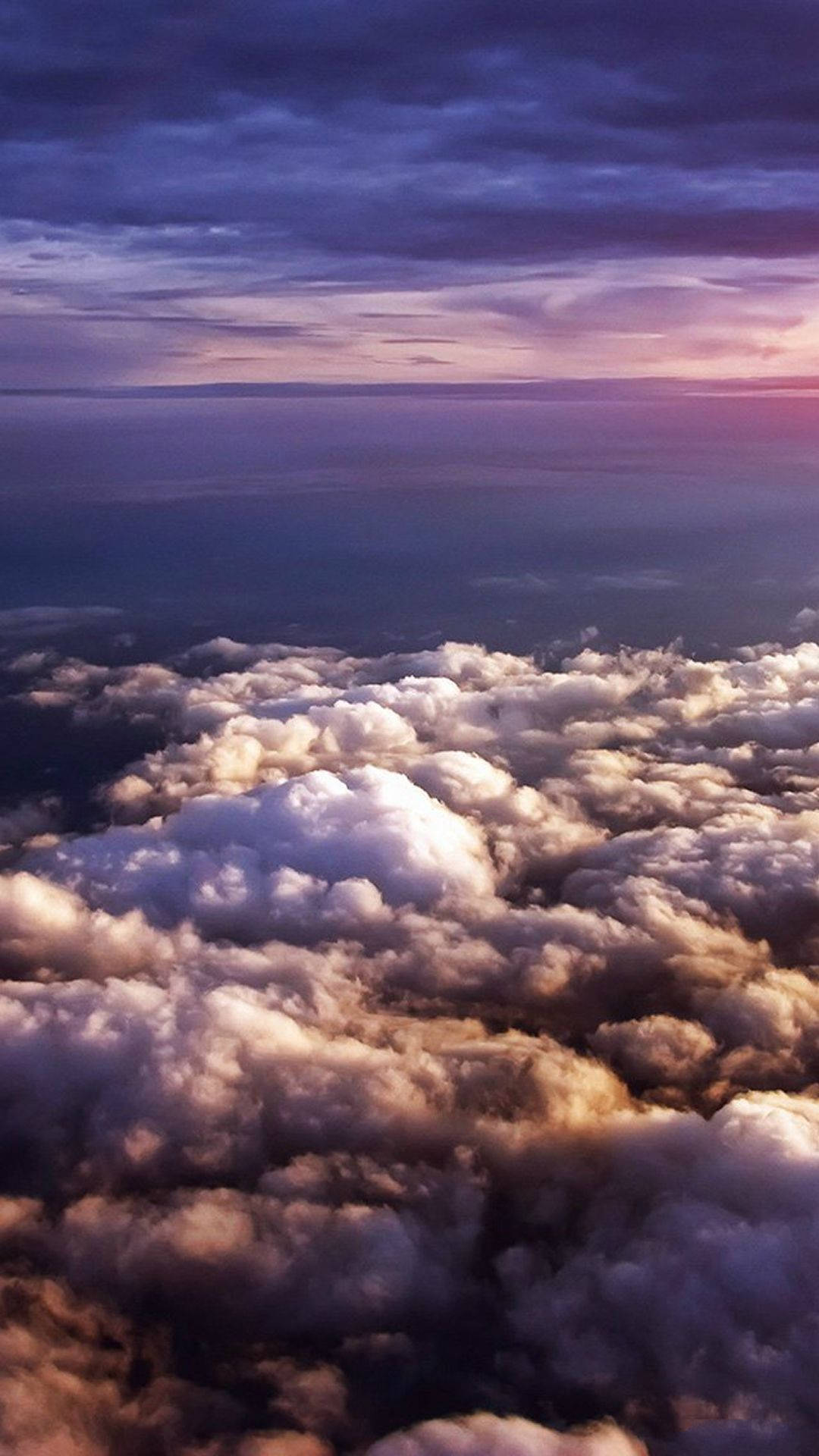 紫雲天際 壁紙 — 從高空俯瞰，蓬鬆的雲朵沐浴在金黃色的日落光芒中，映襯著深紫色的暮色天空。