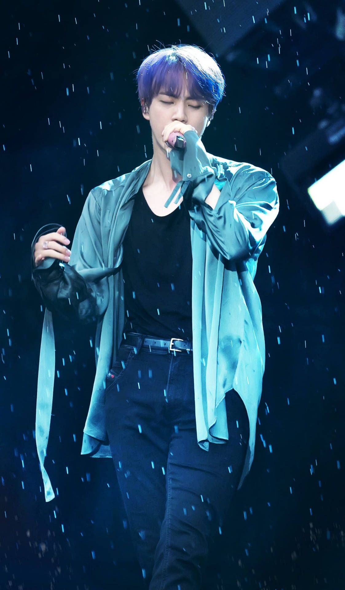 紫髮歌手在藍色燈光下配合雨效表演。