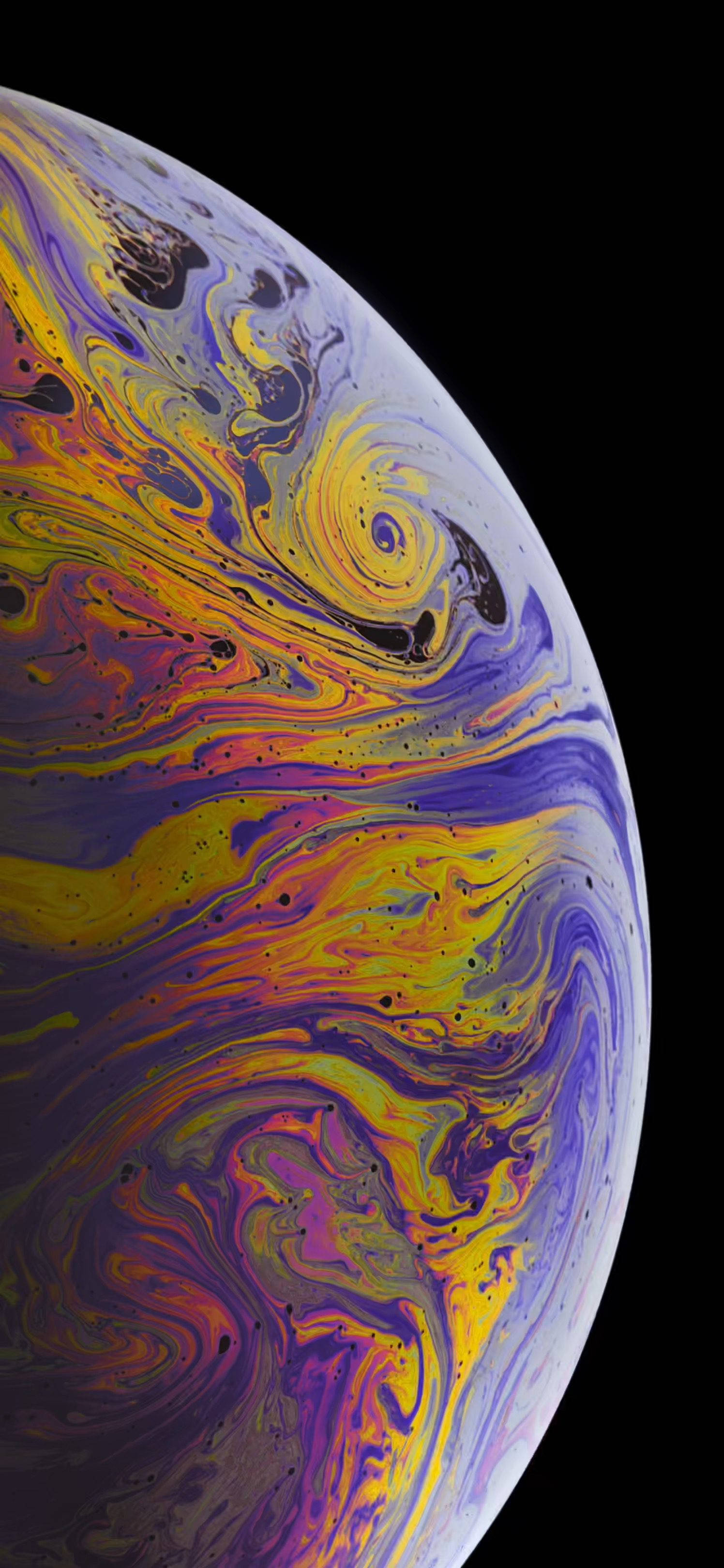 紫黃色星球 iPhone 13 Pro 壁紙 — 一個充滿活力的旋轉肥皂泡，帶有虹彩黃色、紫色和粉紅色，襯托在純黑色背景上。