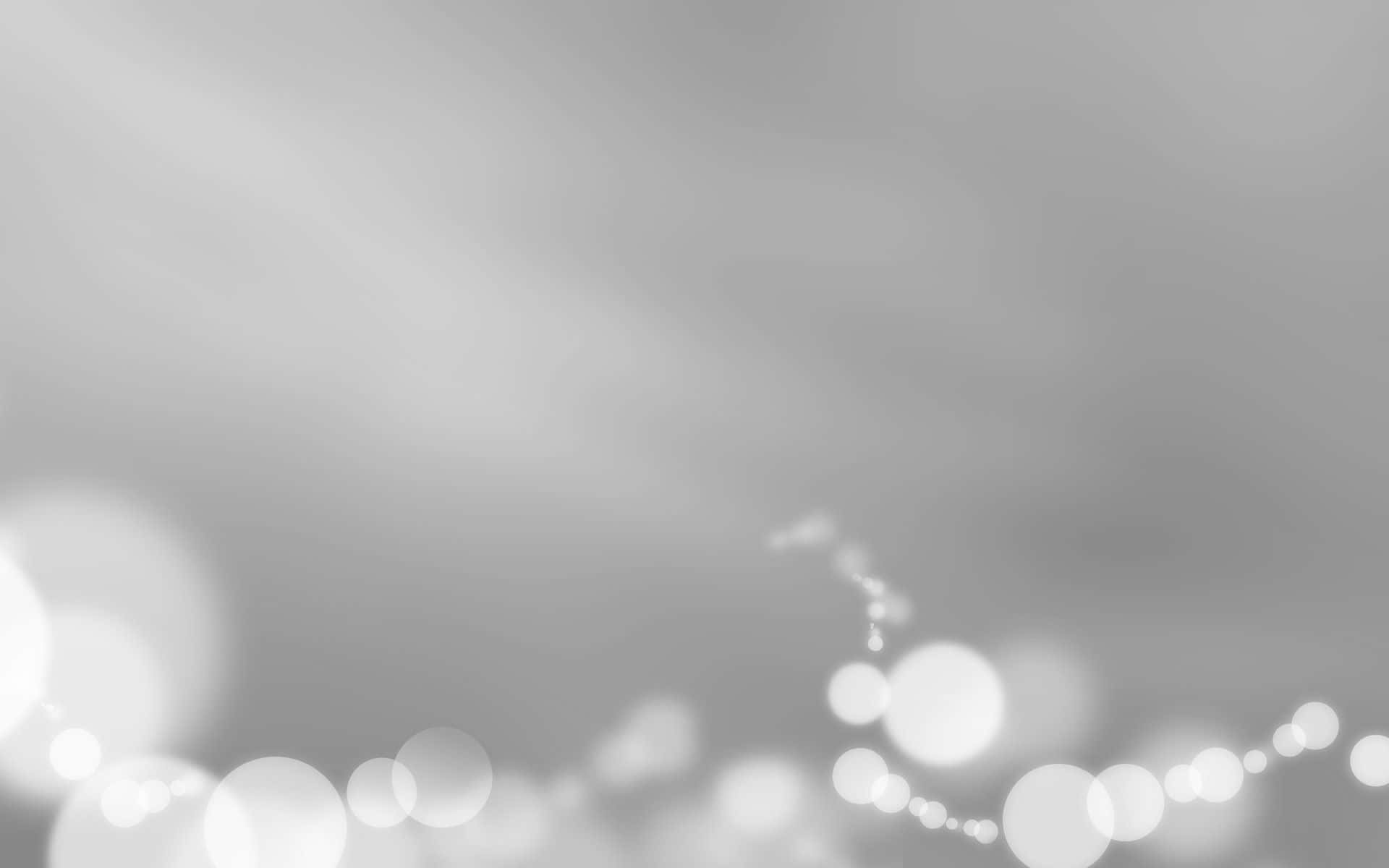 細膩卻堅固：淺灰色背景 壁紙 — 底部帶有散落發光散景燈光的柔和灰色漸變背景。