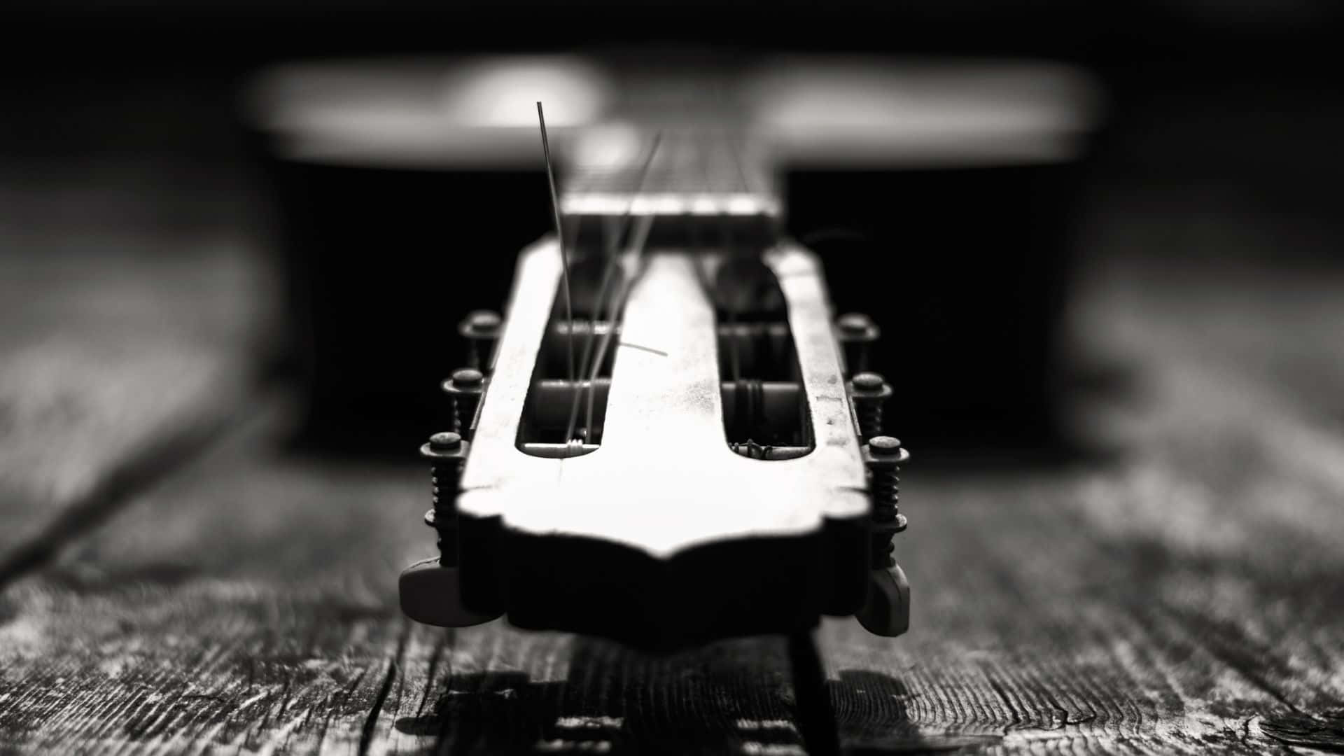 Black And White Guitar 桌布 壁紙 — 結他頭部特寫黑白照片，放置於經風化的木質表面上，景深較淺。