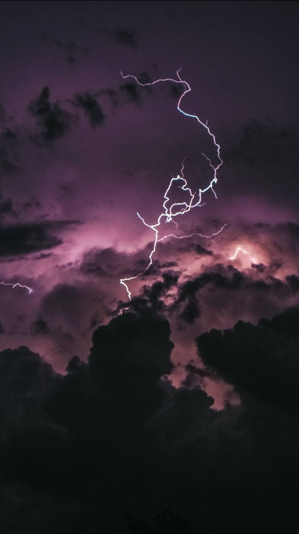 閃電劃過黑暗的暴風雨天空，伴隨著紫色的雲層。