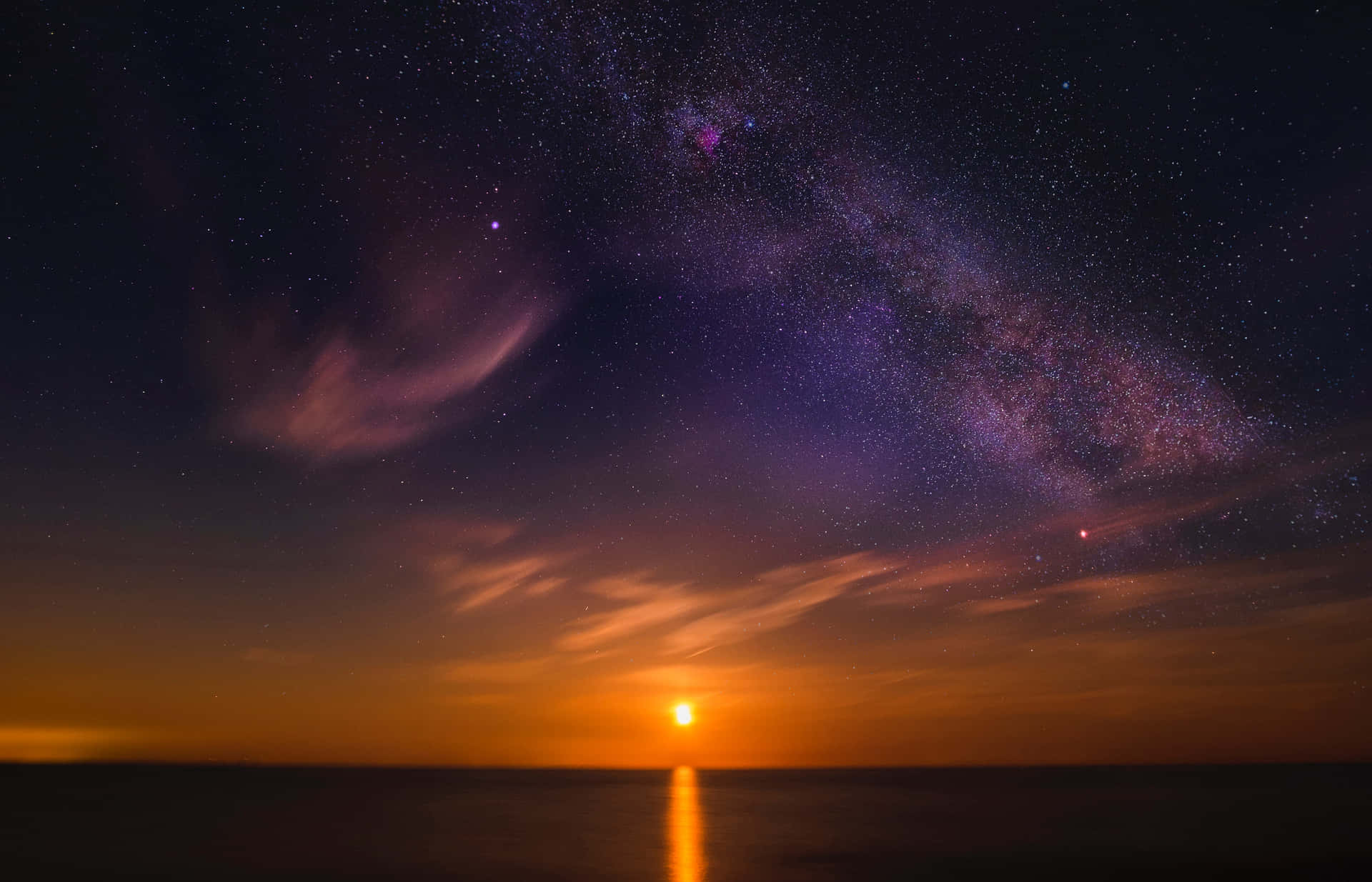 銀河在平靜海面上反射的夕陽餘暉上方劃出一道弧線。