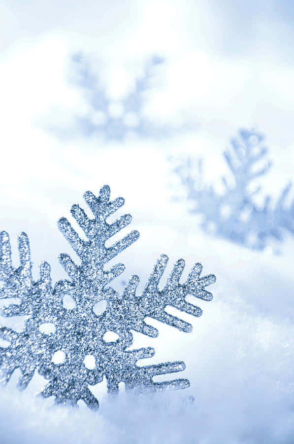 一顆閃亮的銀色雪花躺在雪地上，後面有模糊的雪花。