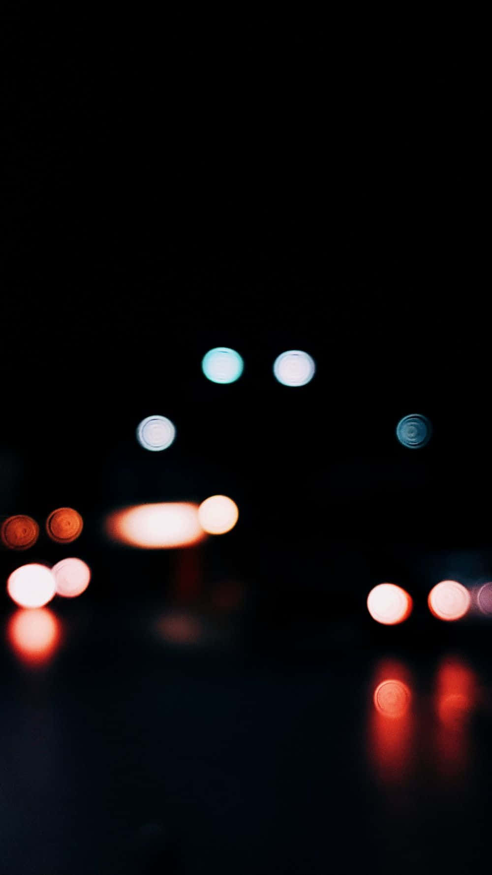 模糊的車燈在潮濕的夜路上發光。