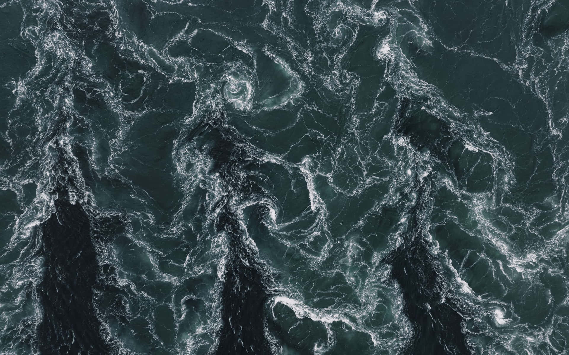 從上方看到的深綠色洶湧海浪與白色泡沫旋轉。